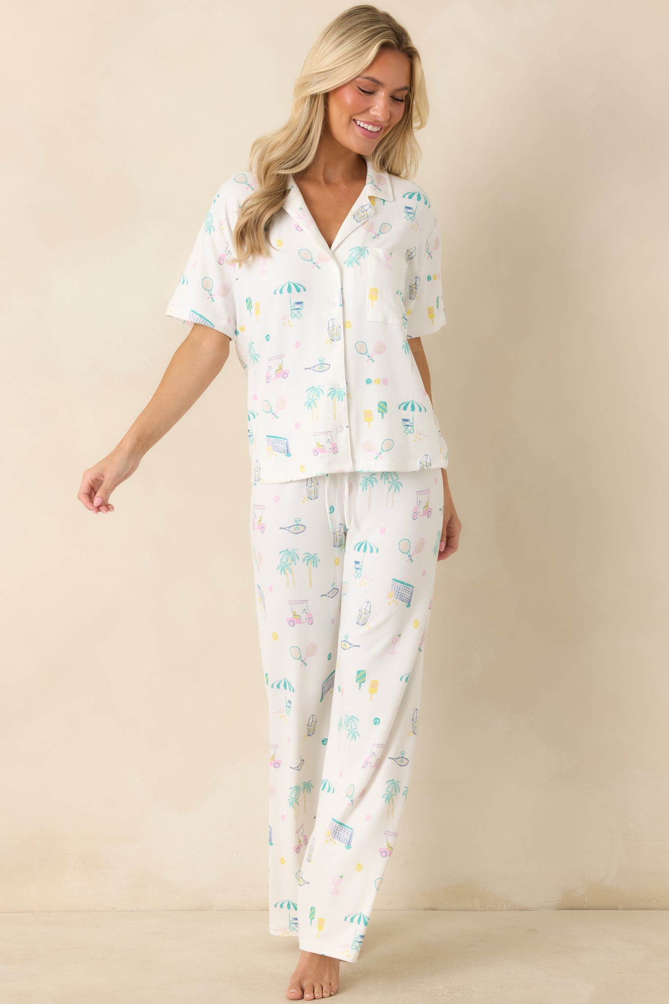 White short-sleeve button-up pajama top featuring soft jersey fabric and a colorful vacation-themed pattern with a laid-back fit.