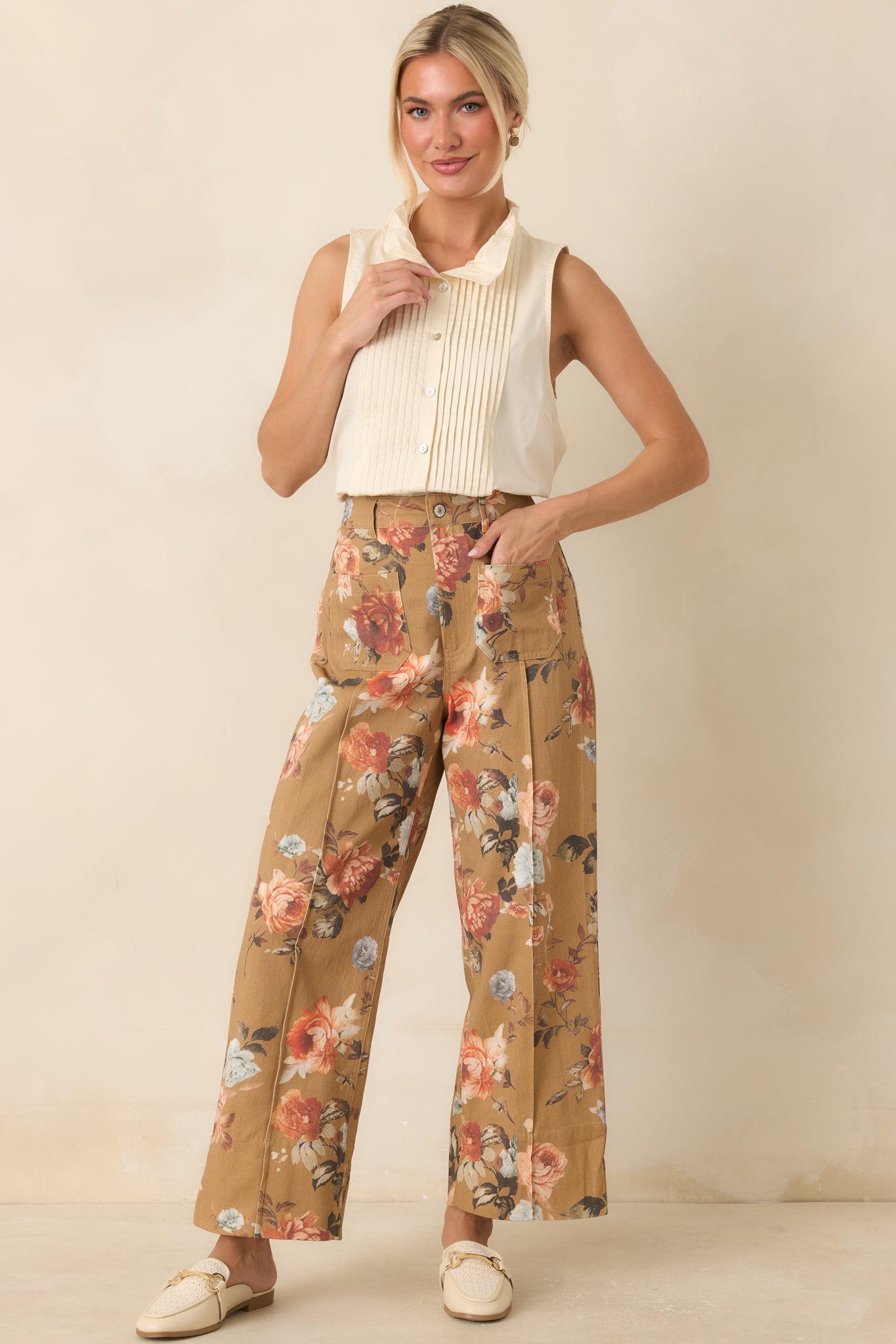 White sleeveless cotton blouse with pintuck pleats, a softly structured collar, and a functional button-front design.