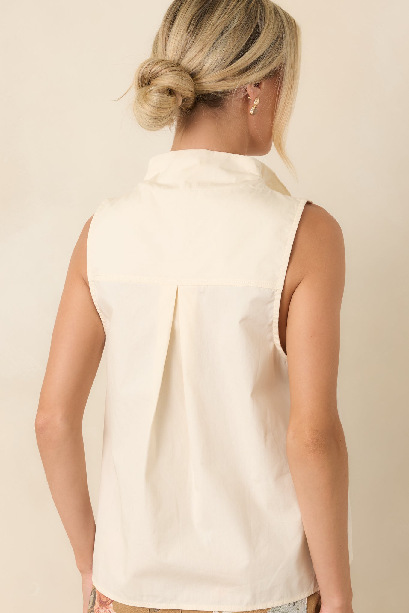 Back view of the white sleeveless cotton blouse featuring a clean, streamlined silhouette and softly tailored finish.