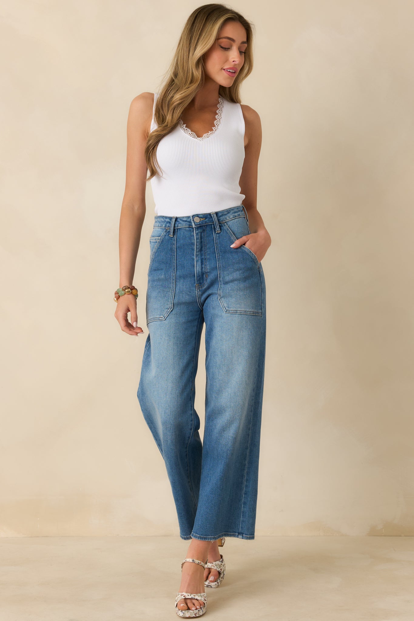 White stretch knit tank designed with vertical ribbing, a feminine lace-trim V-neckline, and a sleek fitted shape.