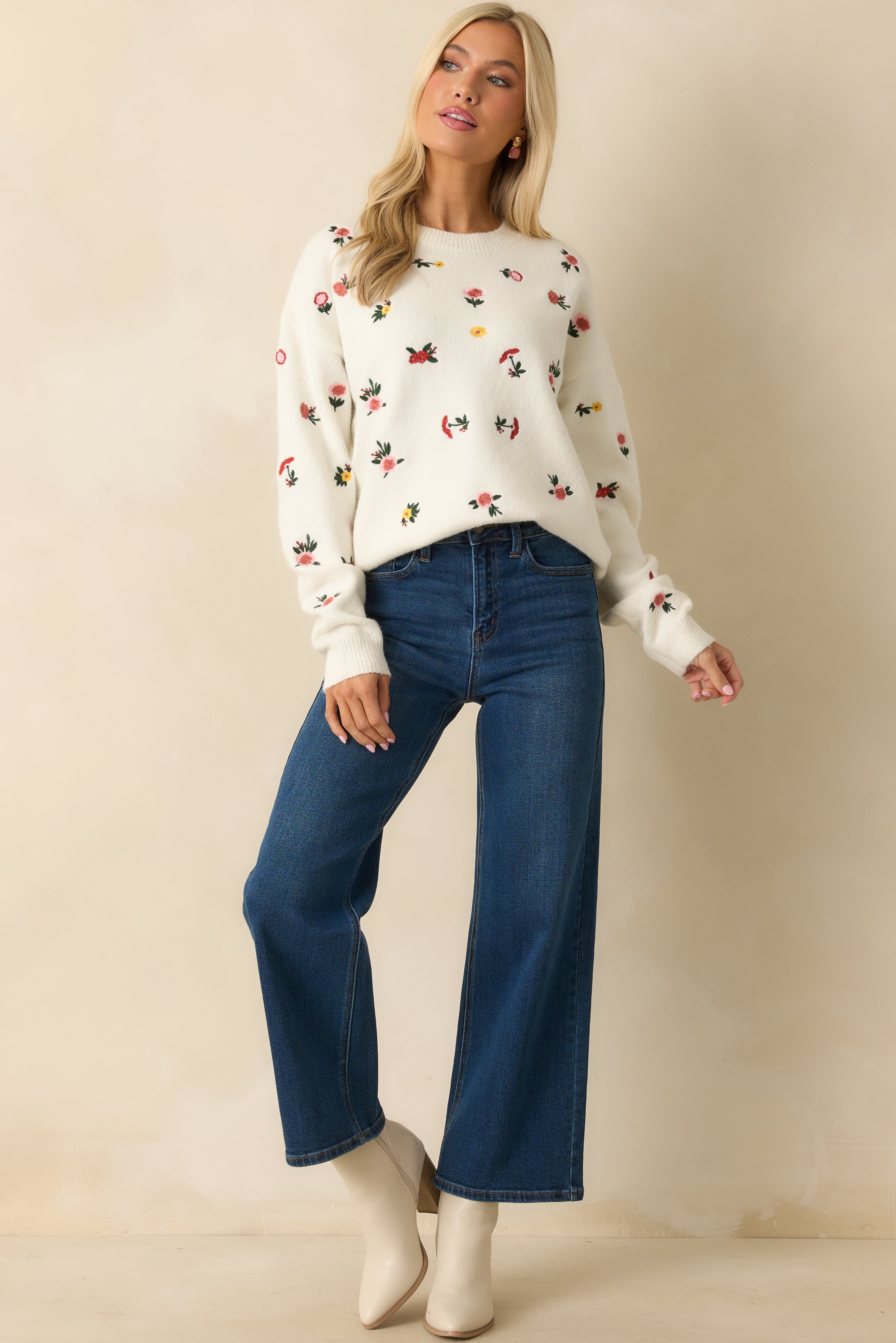 White sweater with long sleeves, floral detailing, and ribbed edges for a polished look.