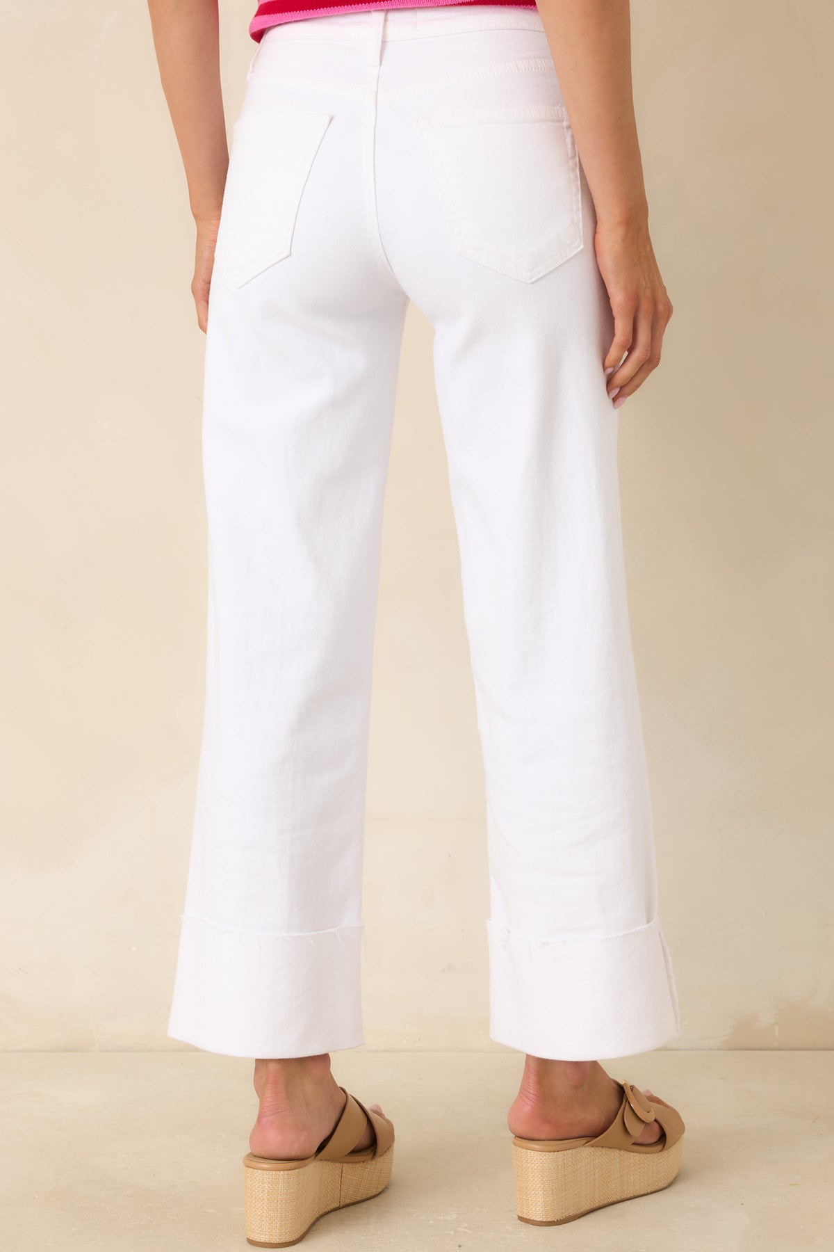 Back view of white wide-leg jeans featuring classic back pockets, stretch denim, and cuffed hems.
