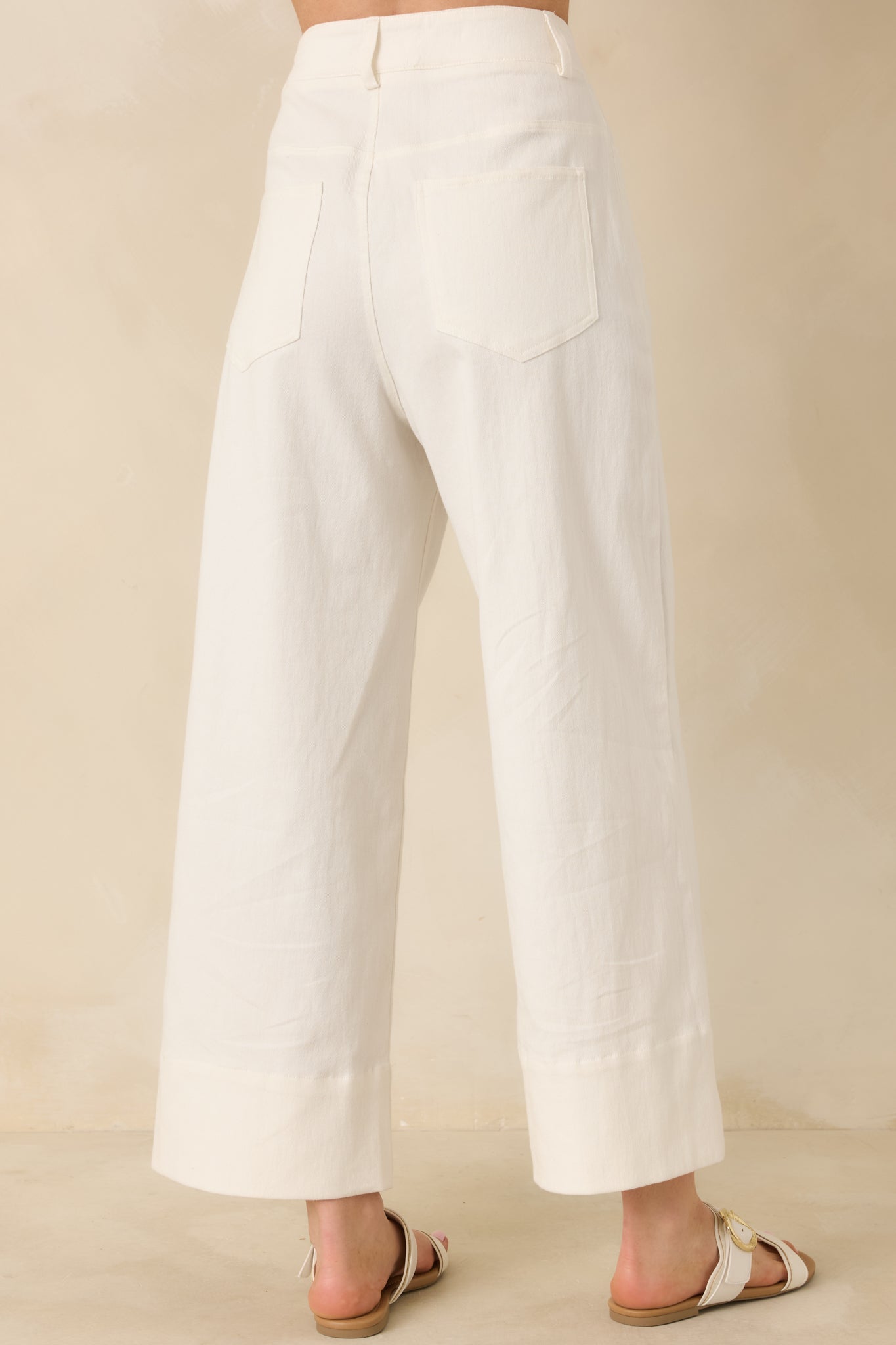 White wide-leg pants with functional rear pockets and a tailored center crease detail.