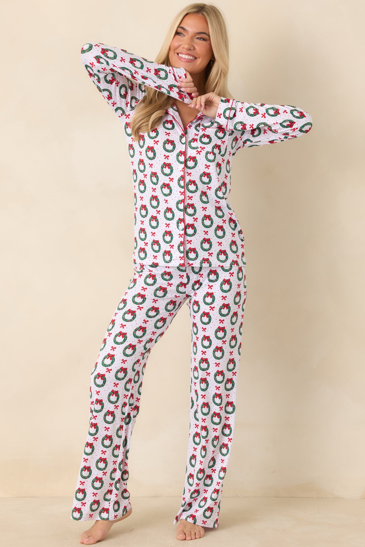 White pajama top features a festive wreath and bow print, red piping, and a classic button-up front.