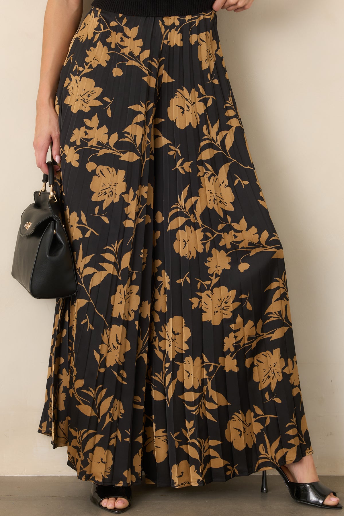 Wide-leg pants featuring golden floral motifs and tightly formed accordion pleats for added texture.
