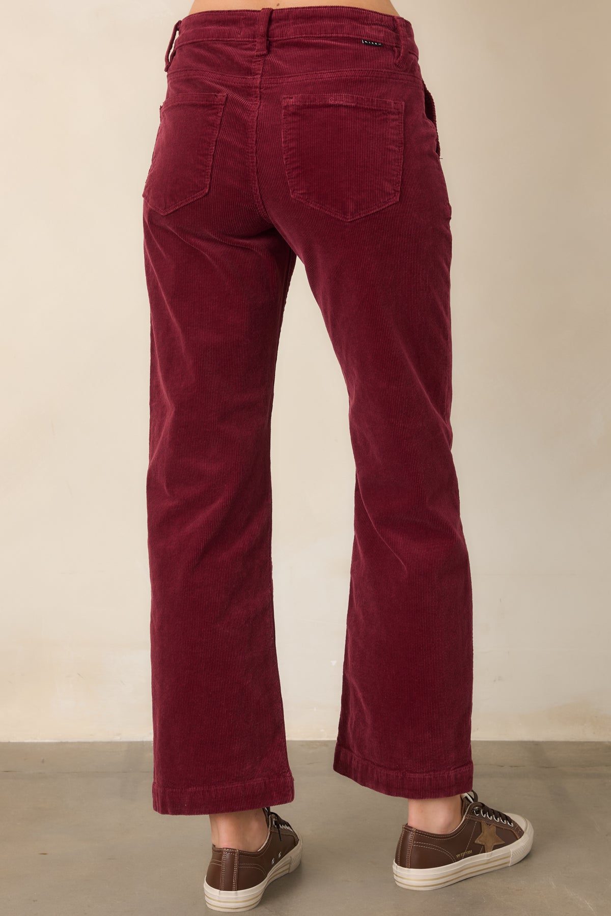 Rear of the wine corduroy pants showing the cropped straight-leg silhouette and practical back patch pockets.