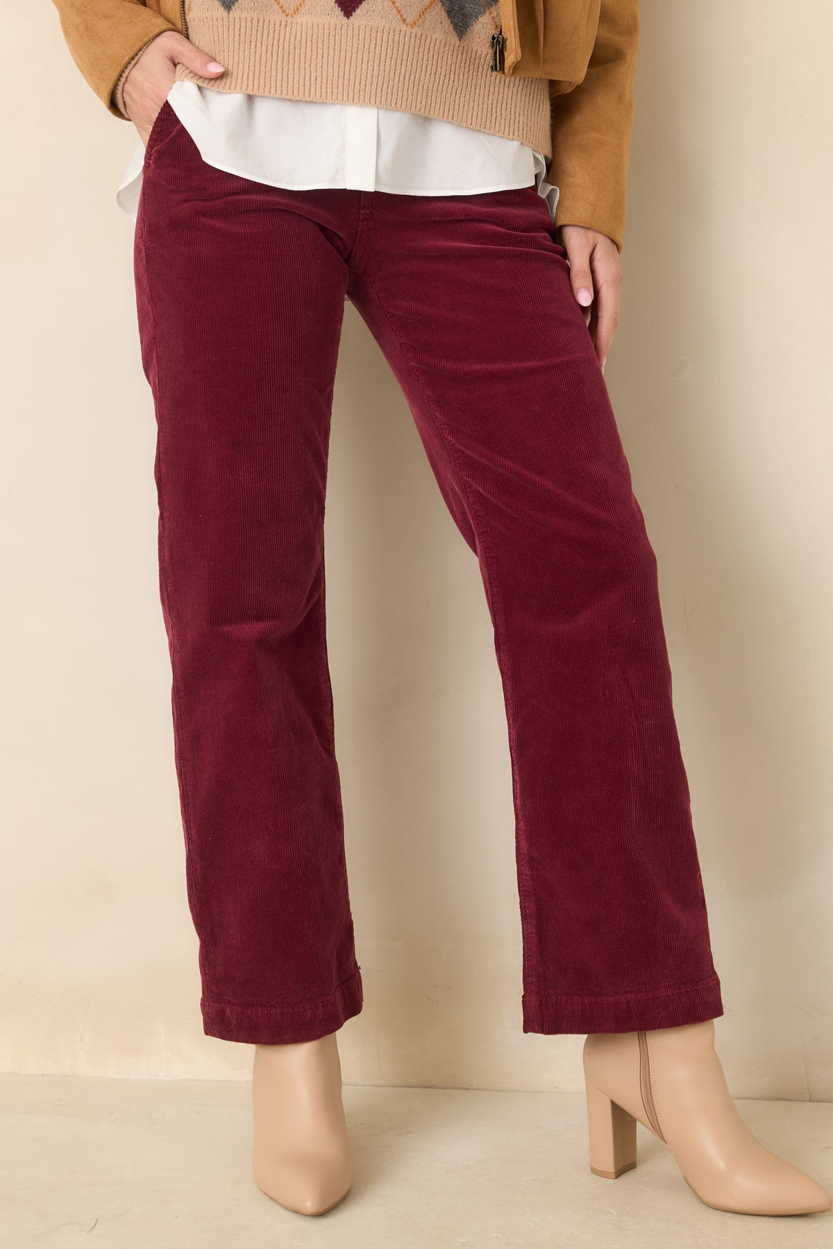 Fine vertical corduroy ribs add texture to the rich wine-colored pants across the front.
