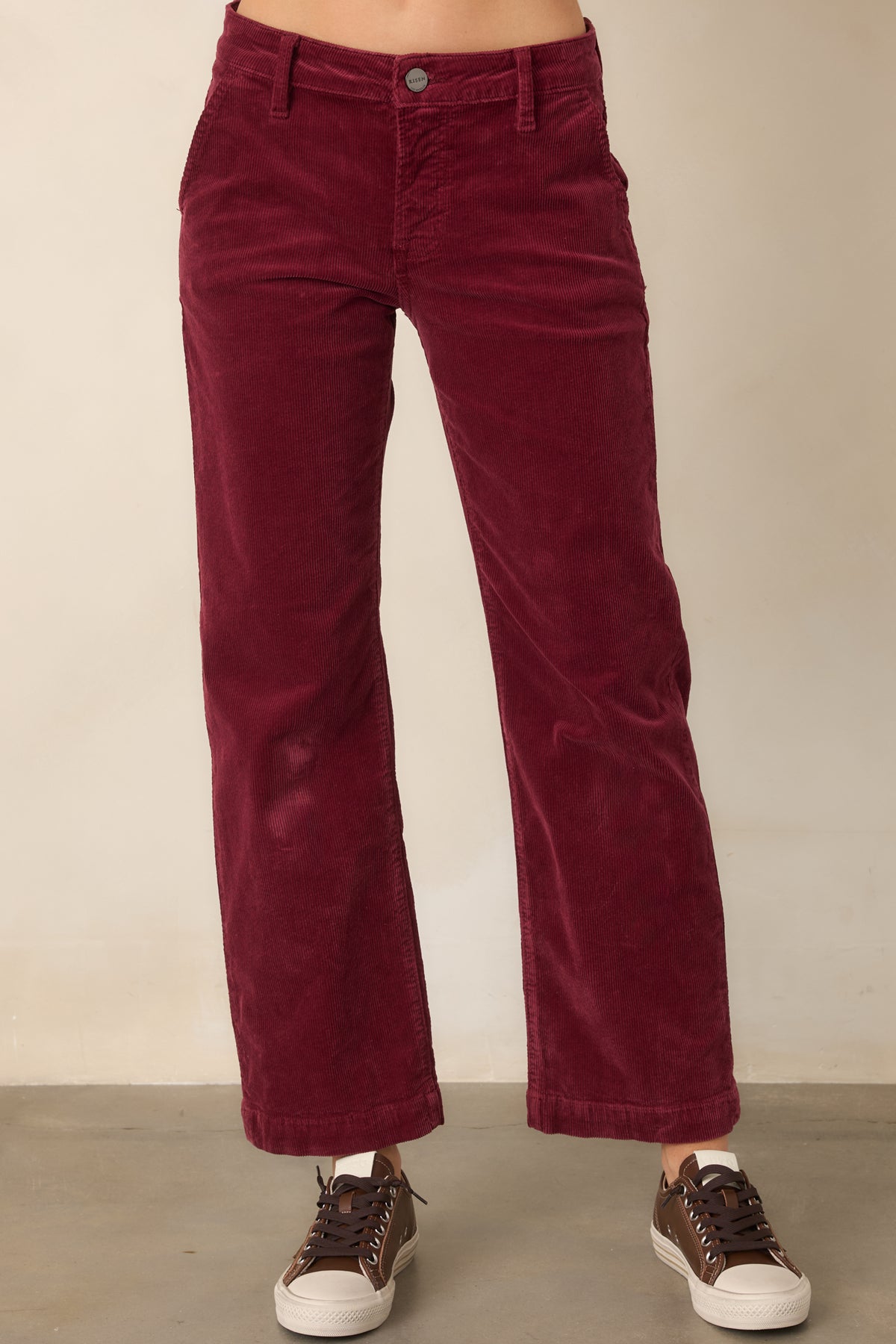 Rich wine corduroy pants with a structured waistband, belt loops, zip fly, button closure, and streamlined straight-leg shape.