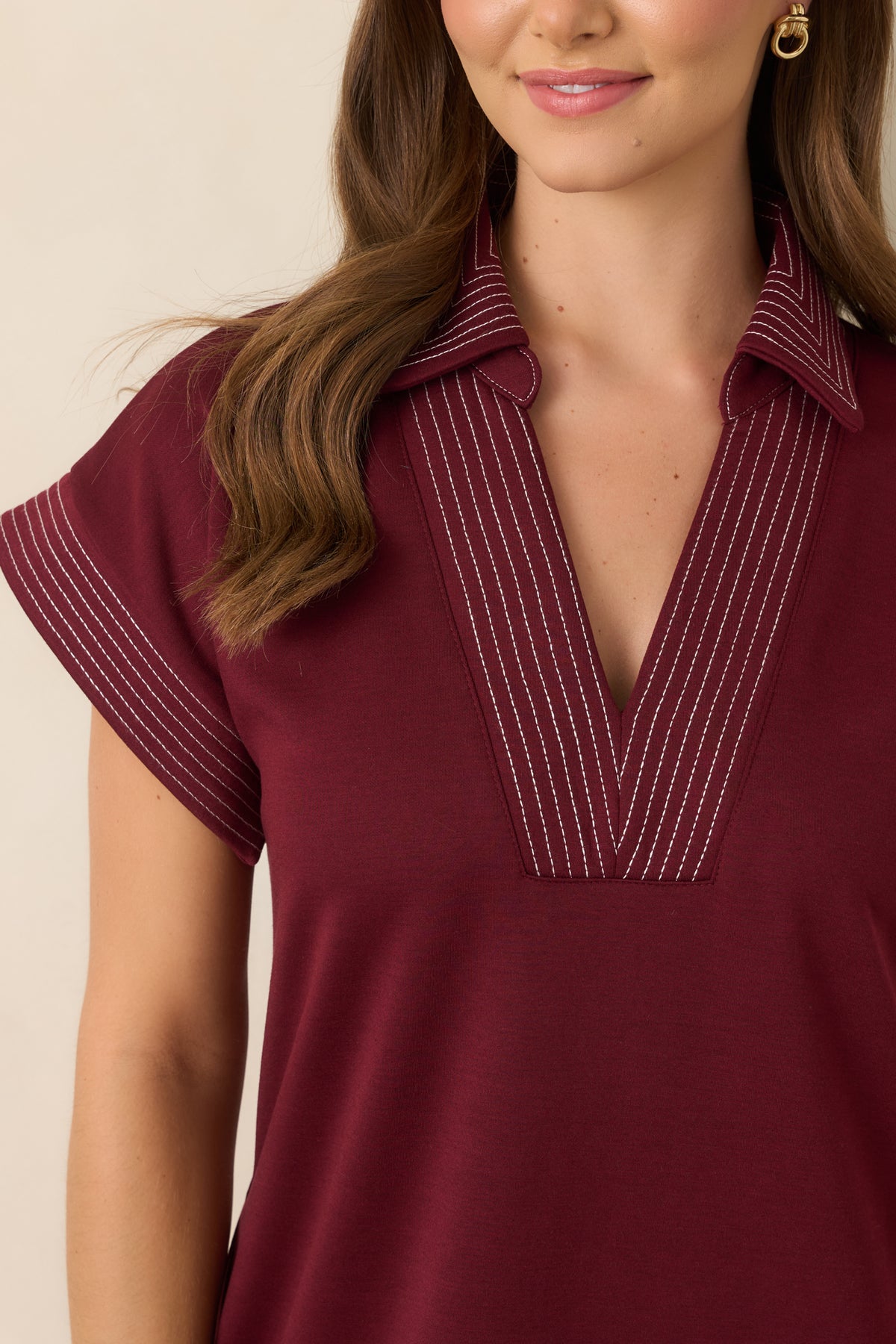 Close-up detail of the wine knit dress showing the collared V-neckline and contrast pinstriped trim.