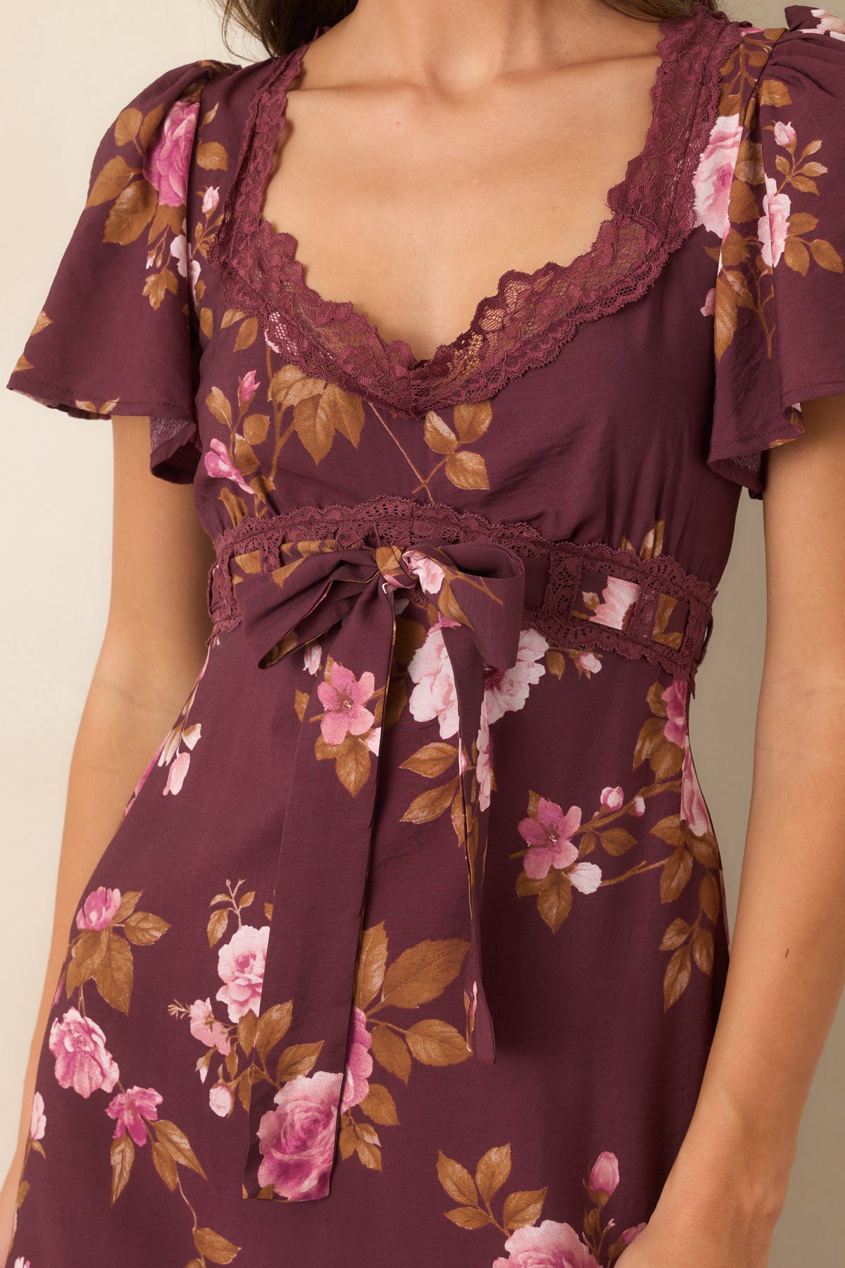 Close-up of the wine floral dress highlighting the scalloped lace along the V-neckline and the pink and blush floral print.