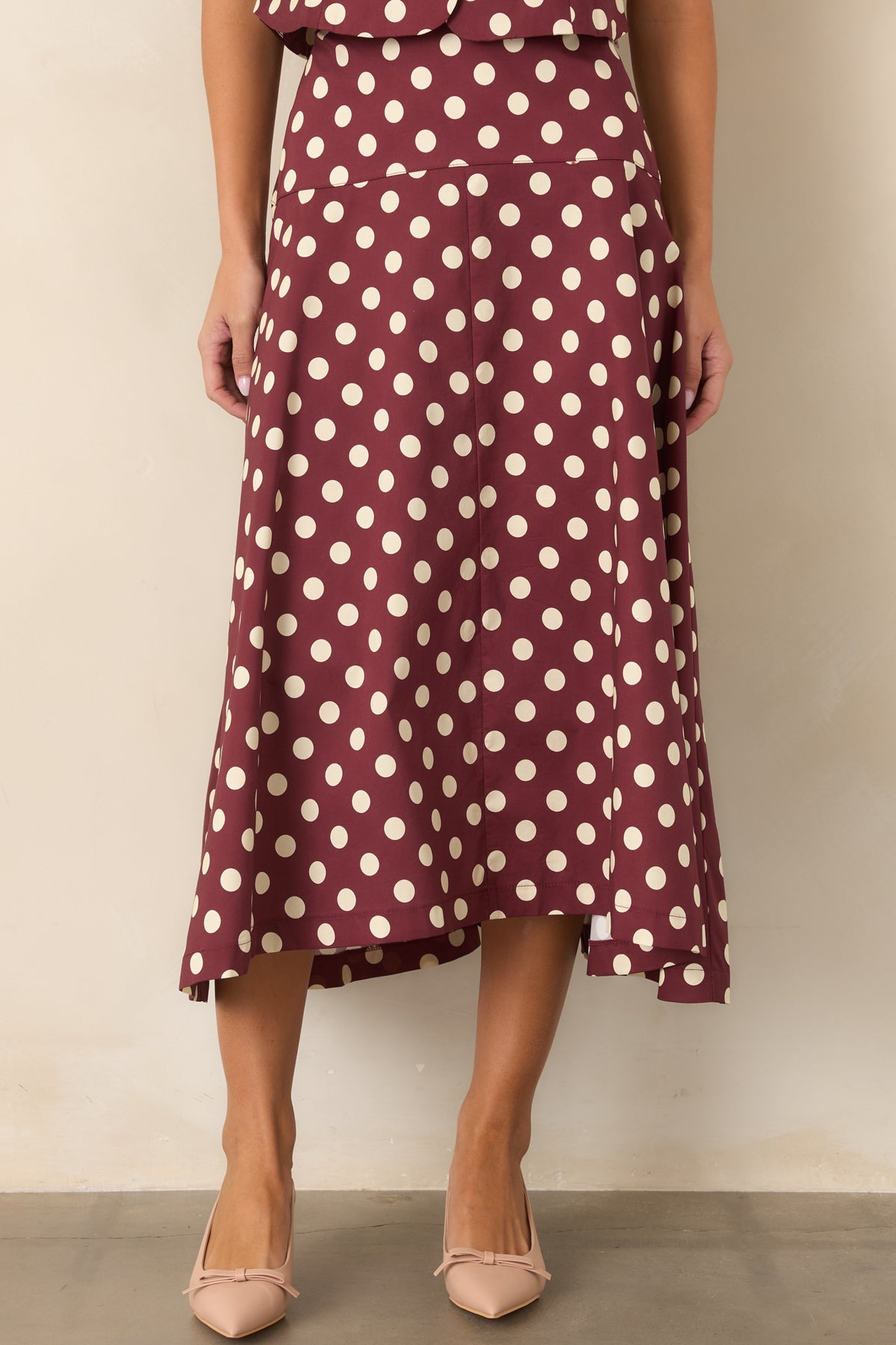 Rich wine midi skirt showcasing its ivory dot pattern and full, flared shape.