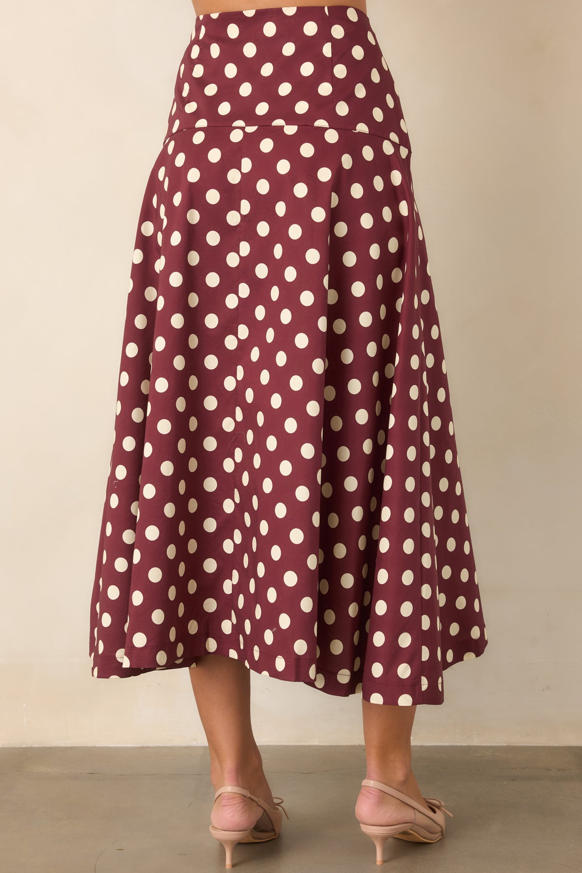 Rear of the wine and ivory dotted cotton midi skirt showing its fitted yoke and full flared shape.