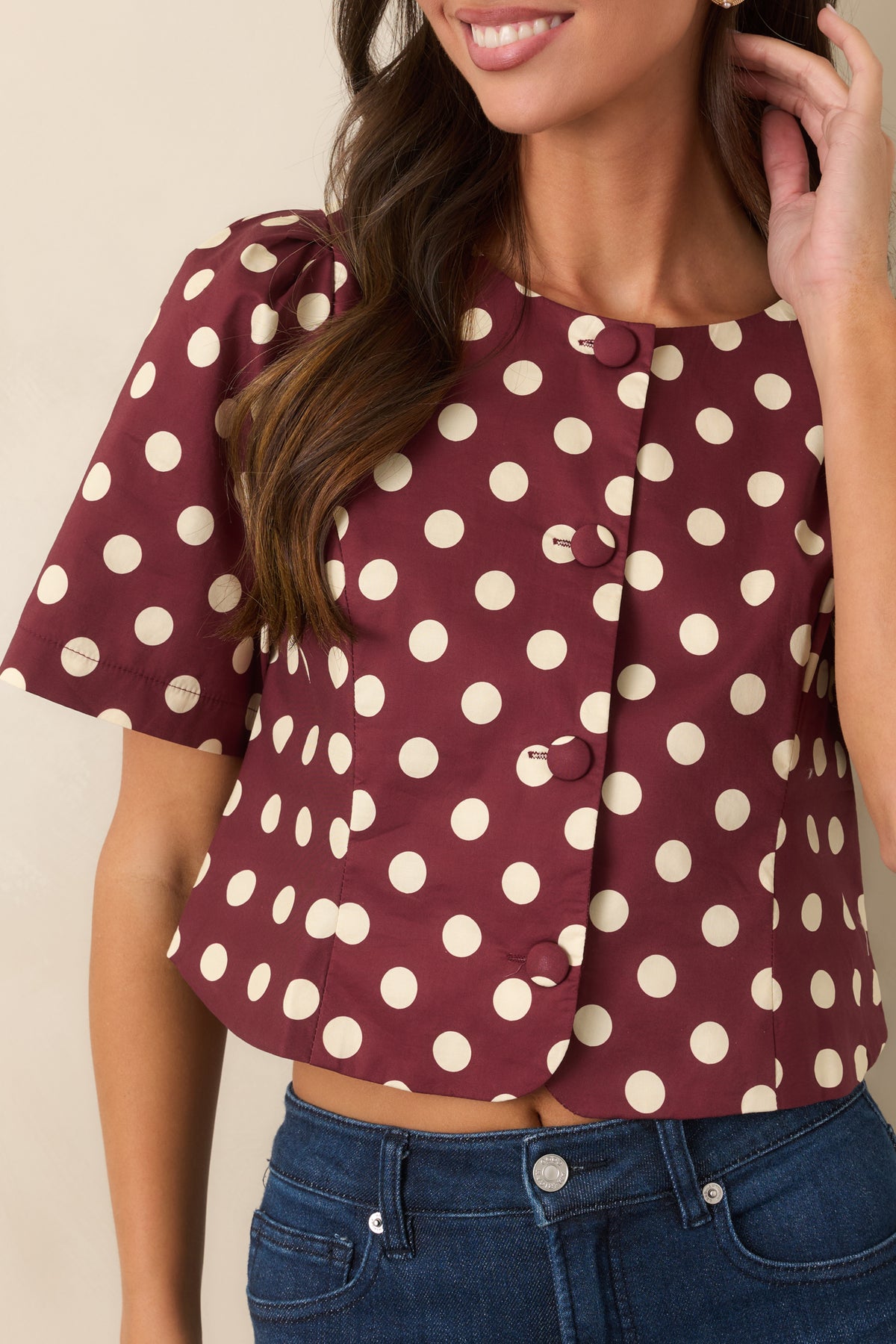 Close-up of the wine cotton top showing the ivory polka dot print and fabric-covered front buttons.