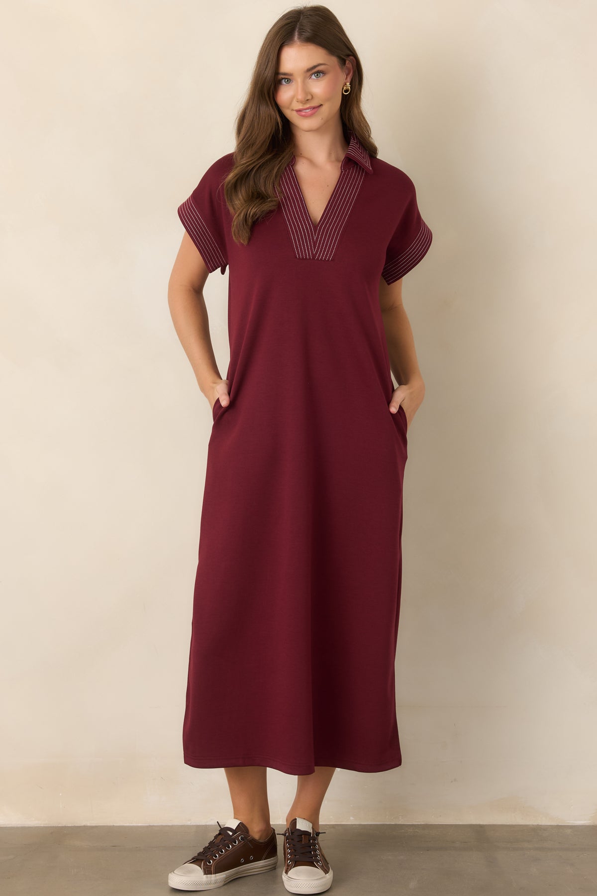 Wine hued knit maxi dress showcasing contrast pinstriping, relaxed proportions, and convenient side pockets.