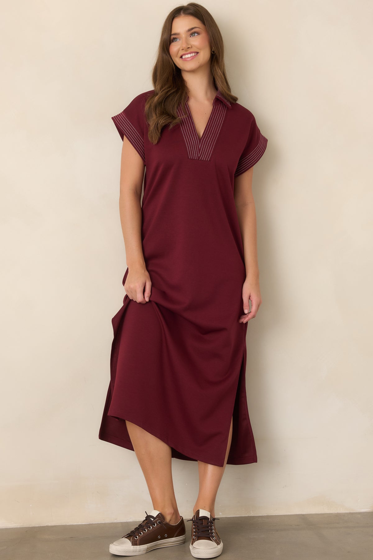 Wine knit maxi dress emphasizing the relaxed silhouette, contrast pinstriped trim, and flowing length.