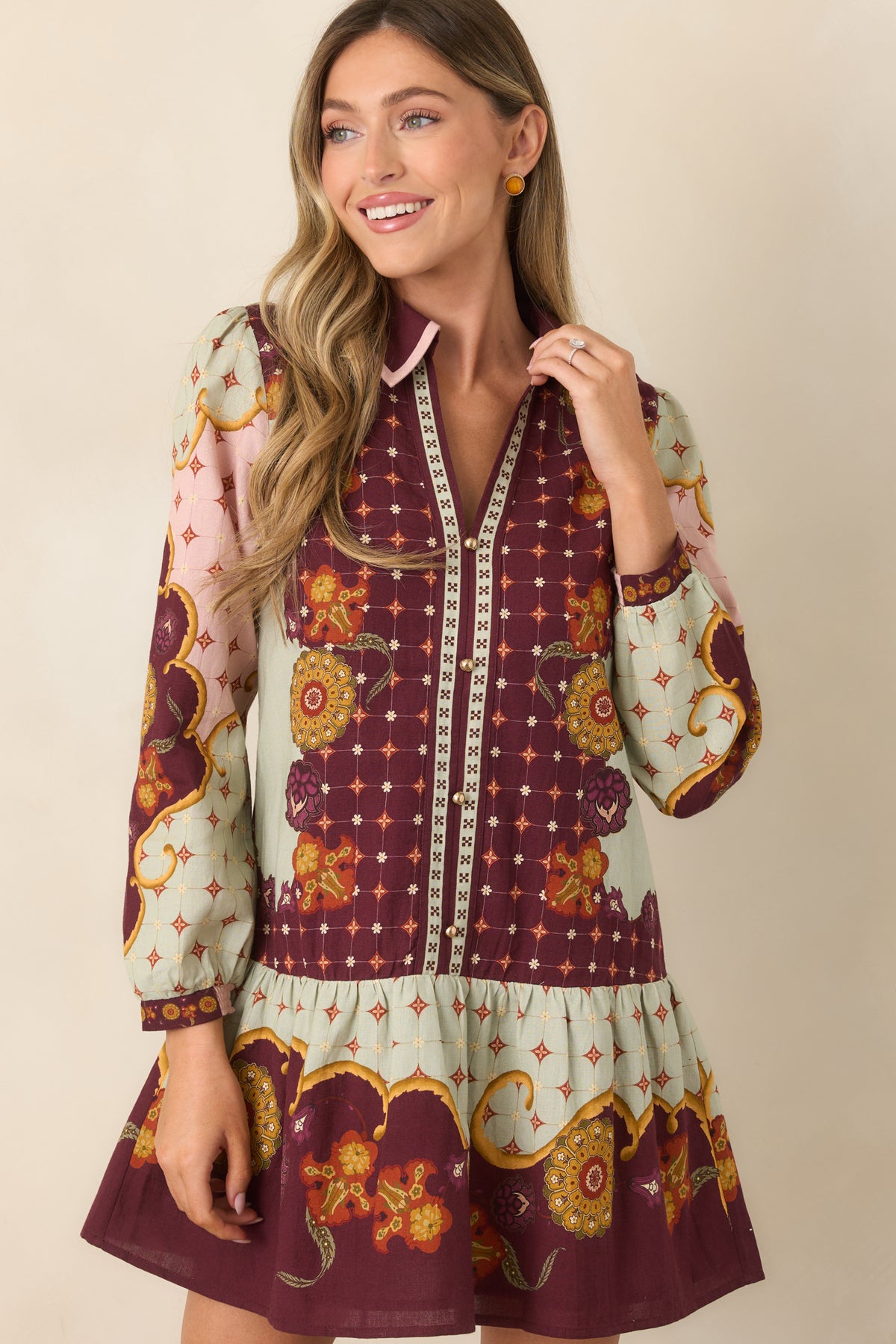 Wine dress highlighted by pink-trimmed split neckline and polished gold-tone buttons along the front placket.