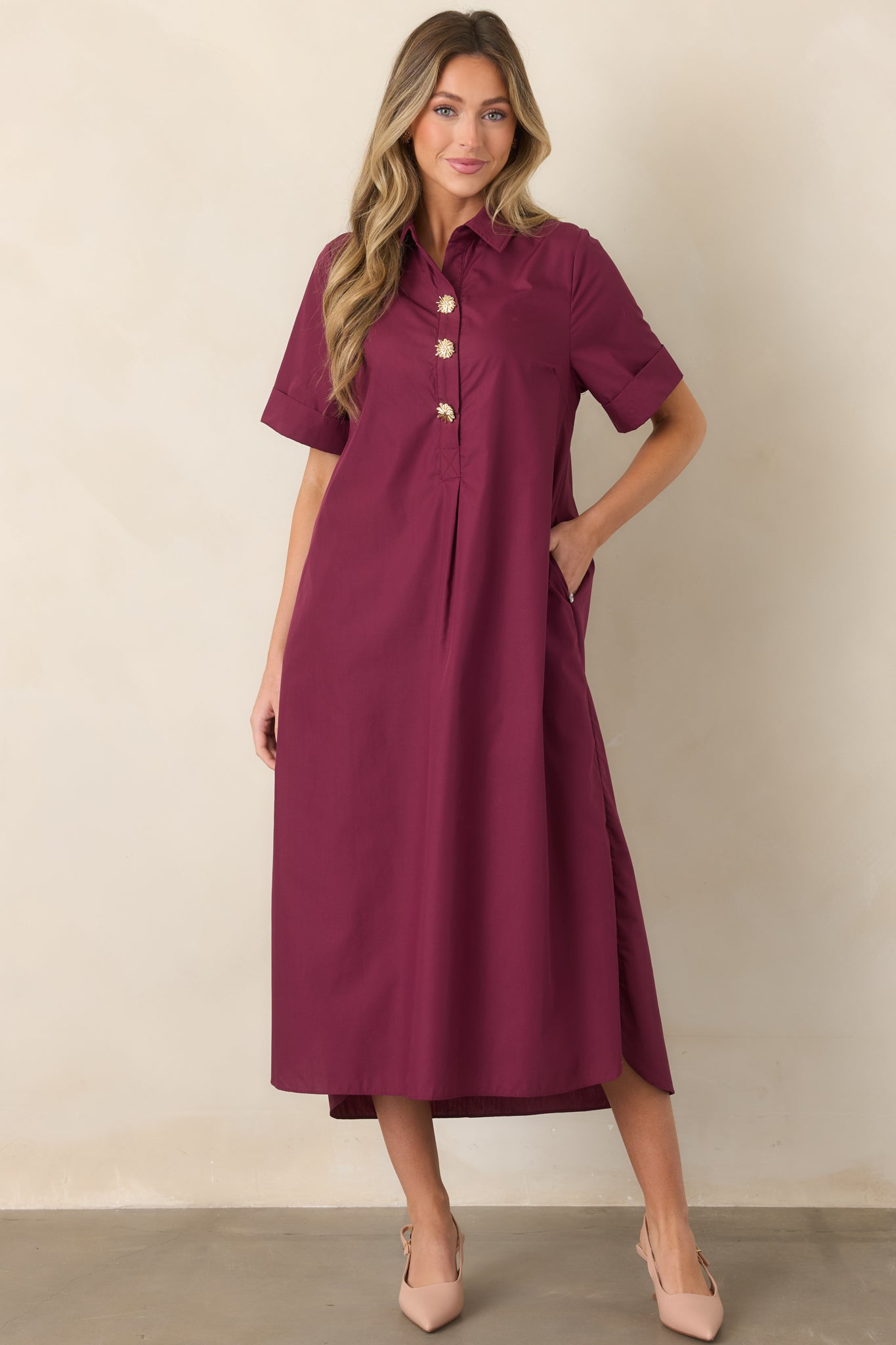 Polished wine red maxi dress featuring eye-catching gold floral buttons, a softly flowing A-line shape, convenient side pockets, and rolled sleeves.