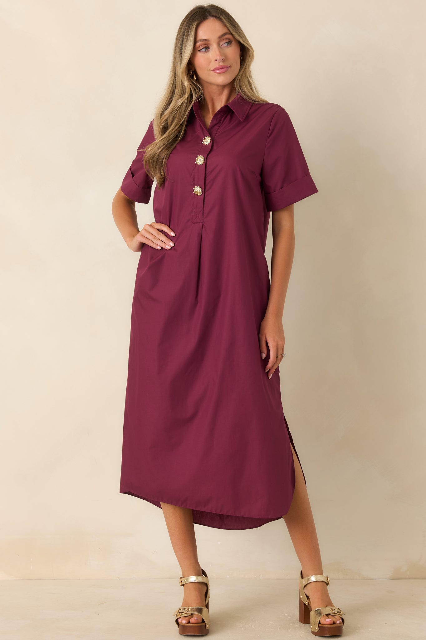 Wine red shirt dress featuring a collared neckline, rolled sleeves, gold floral buttons, and a relaxed flowing maxi silhouette.