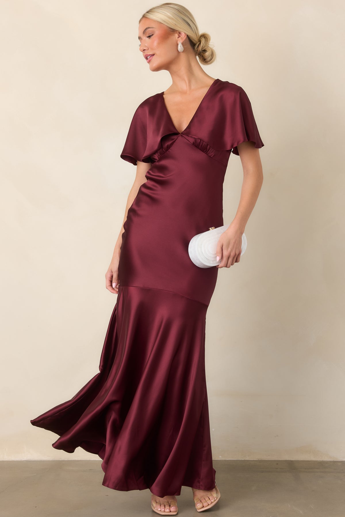 Lustrous wine satin dress showcasing the defined waist and softly flared seamed hem.
