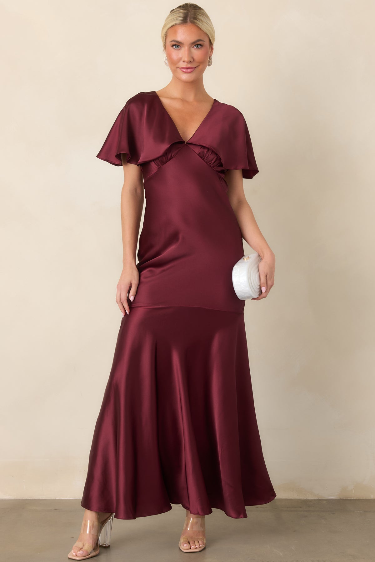 Wine satin dress showcasing its fitted silhouette, flutter sleeves, and softly structured seamed hem.
