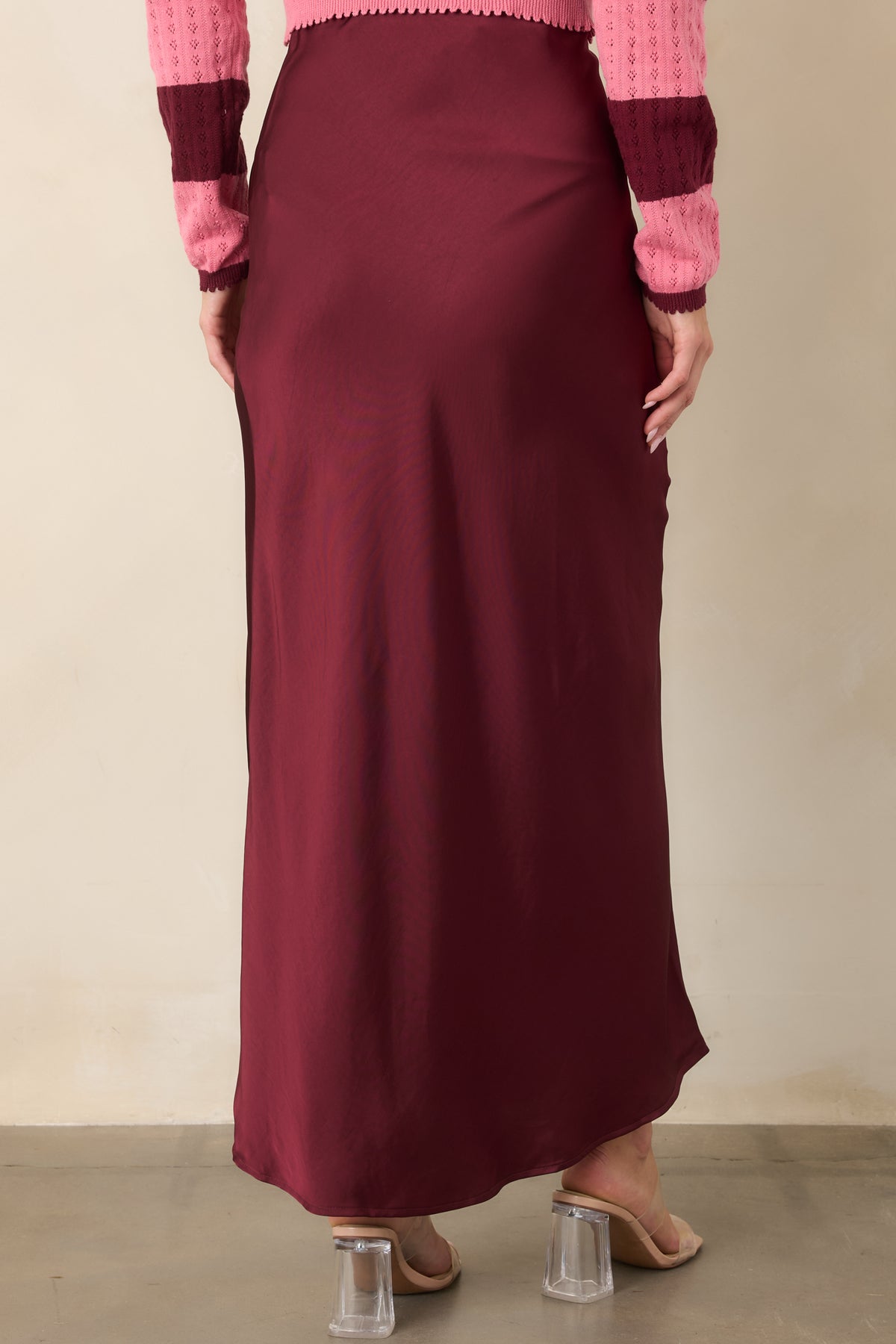 Rear of the rich wine satin midi skirt with a smooth high-rise waist and bias-cut drape.