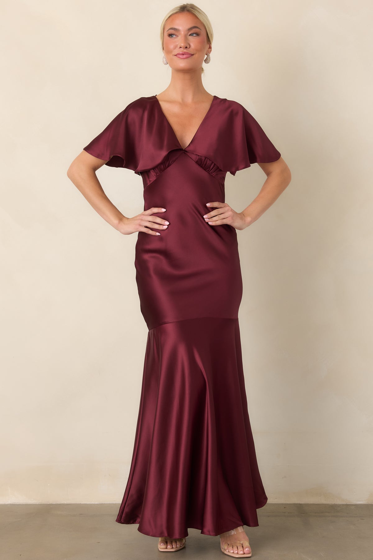 Wine satin maxi dress with a defined waist, flowing flutter sleeves, and softly flared seamed hem.