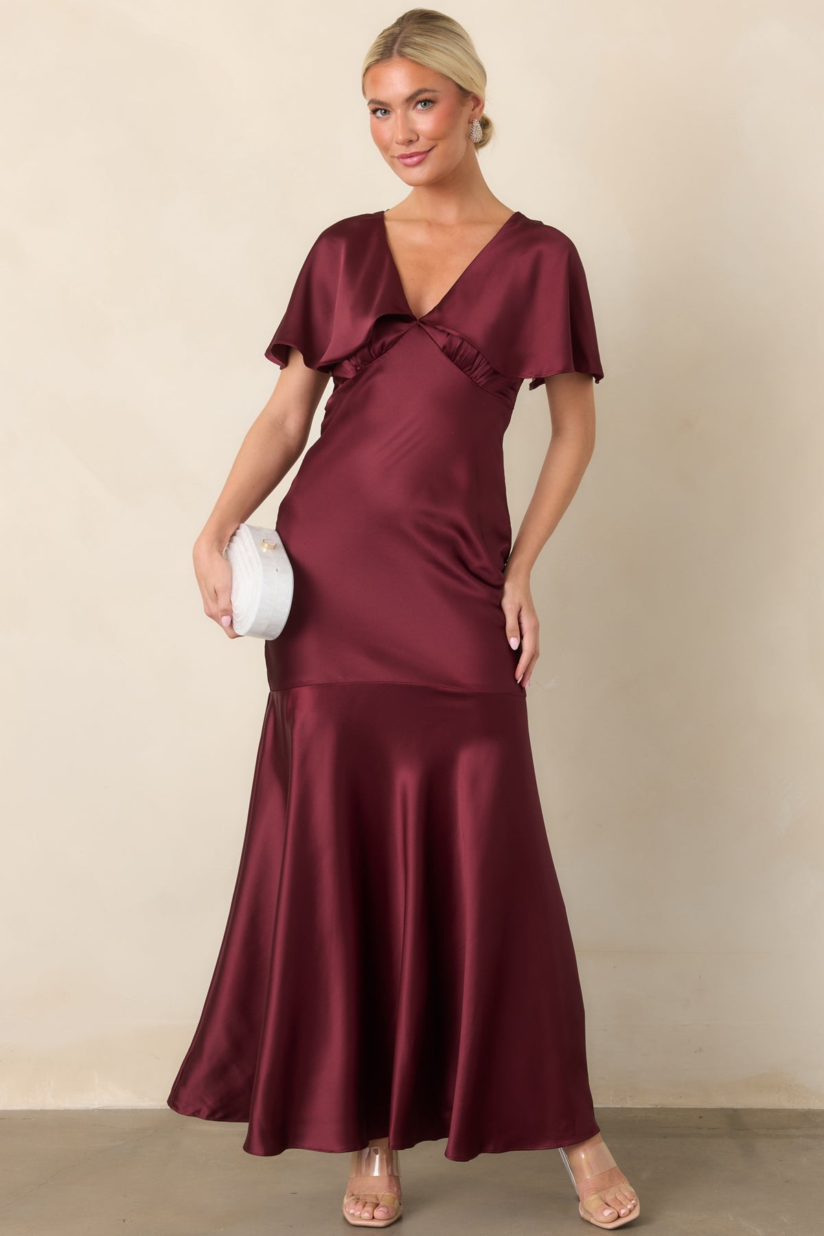 Wine satin maxi dress highlighting the plunging V-neckline, fitted bodice, and elegant flowing shape.