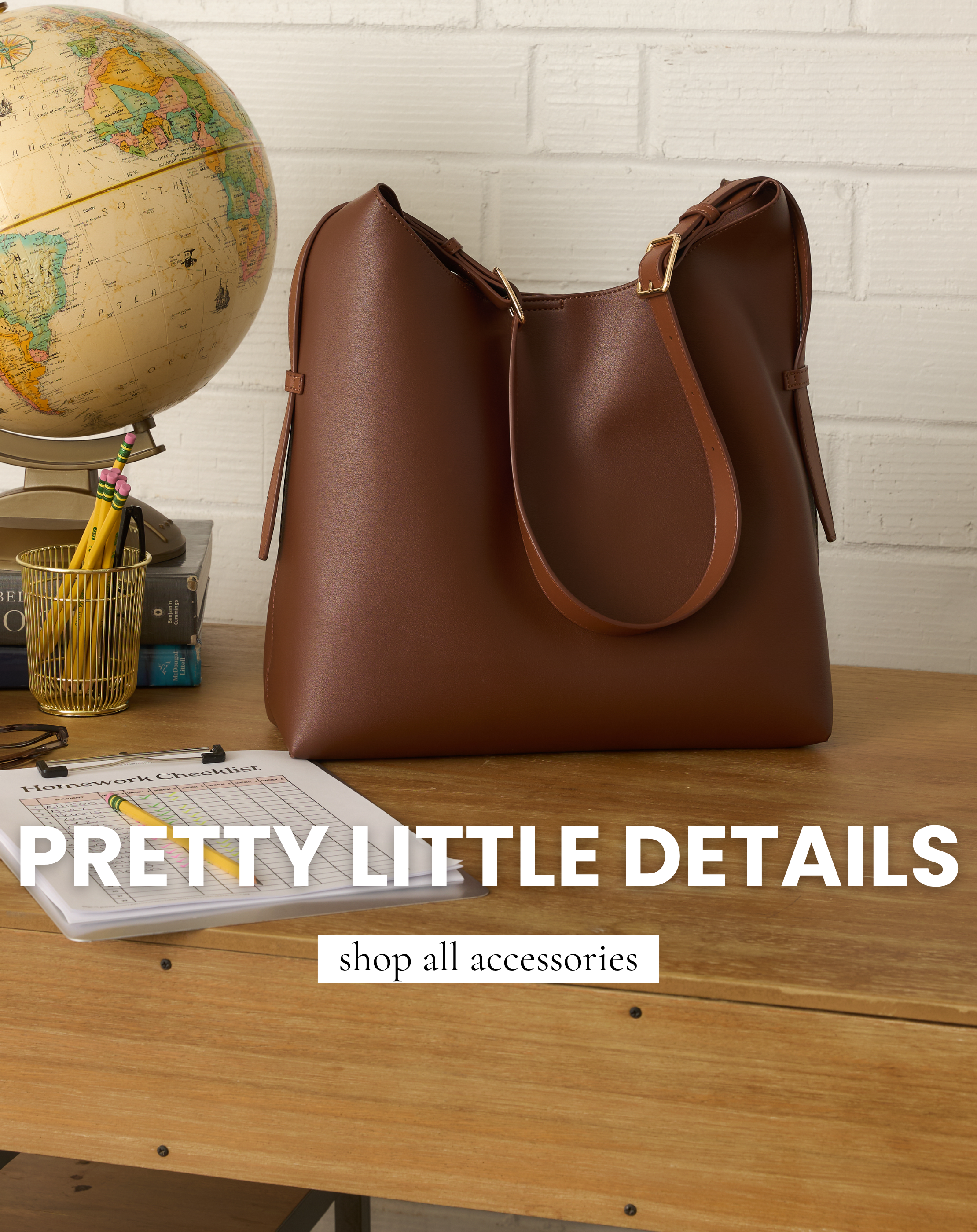 Brown shoulder bag displayed on a wooden desk with classroom-inspired accessories. Bag featured in All Accessories.