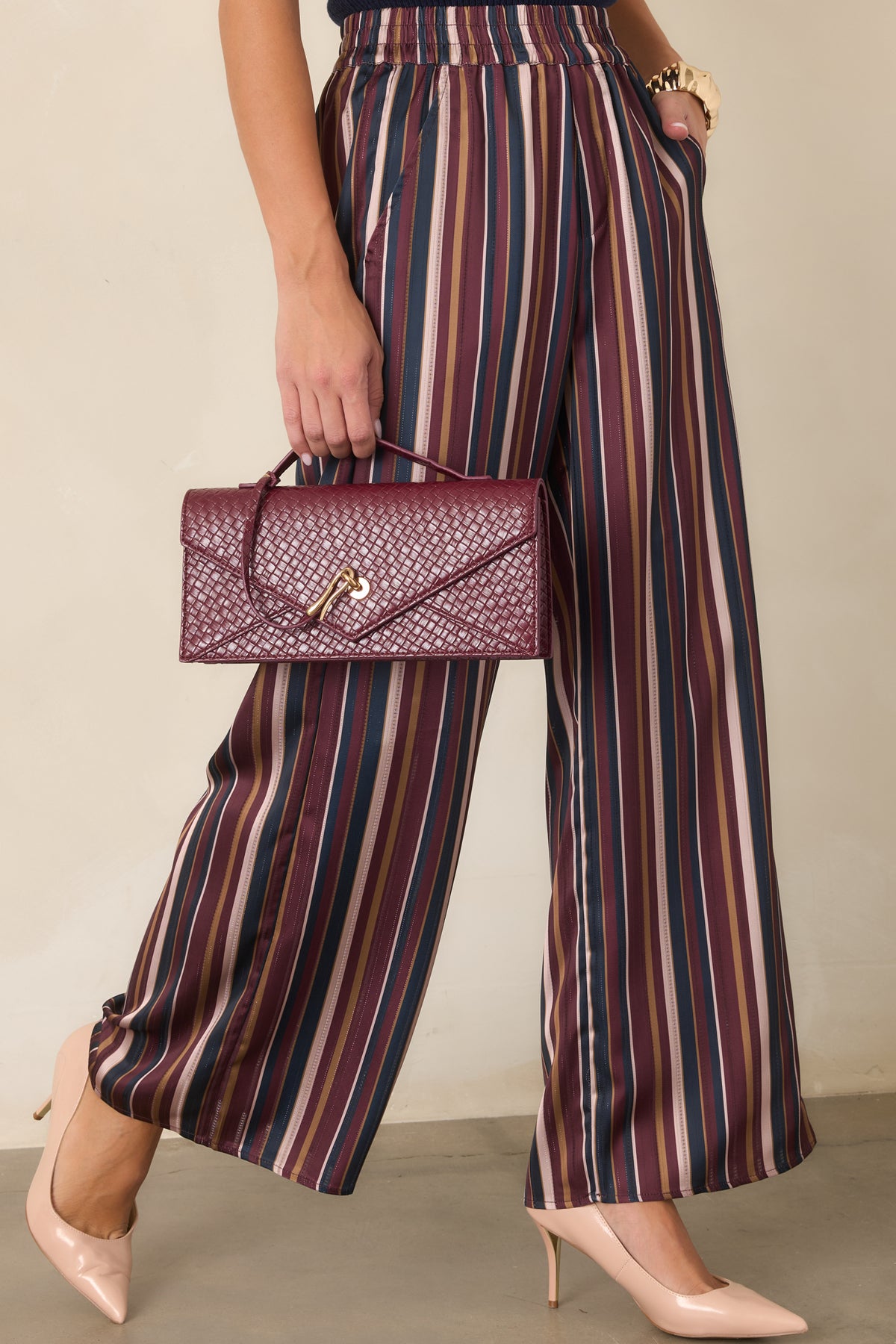 Woven burgundy clutch showcasing the slender top handle and refined envelope silhouette.