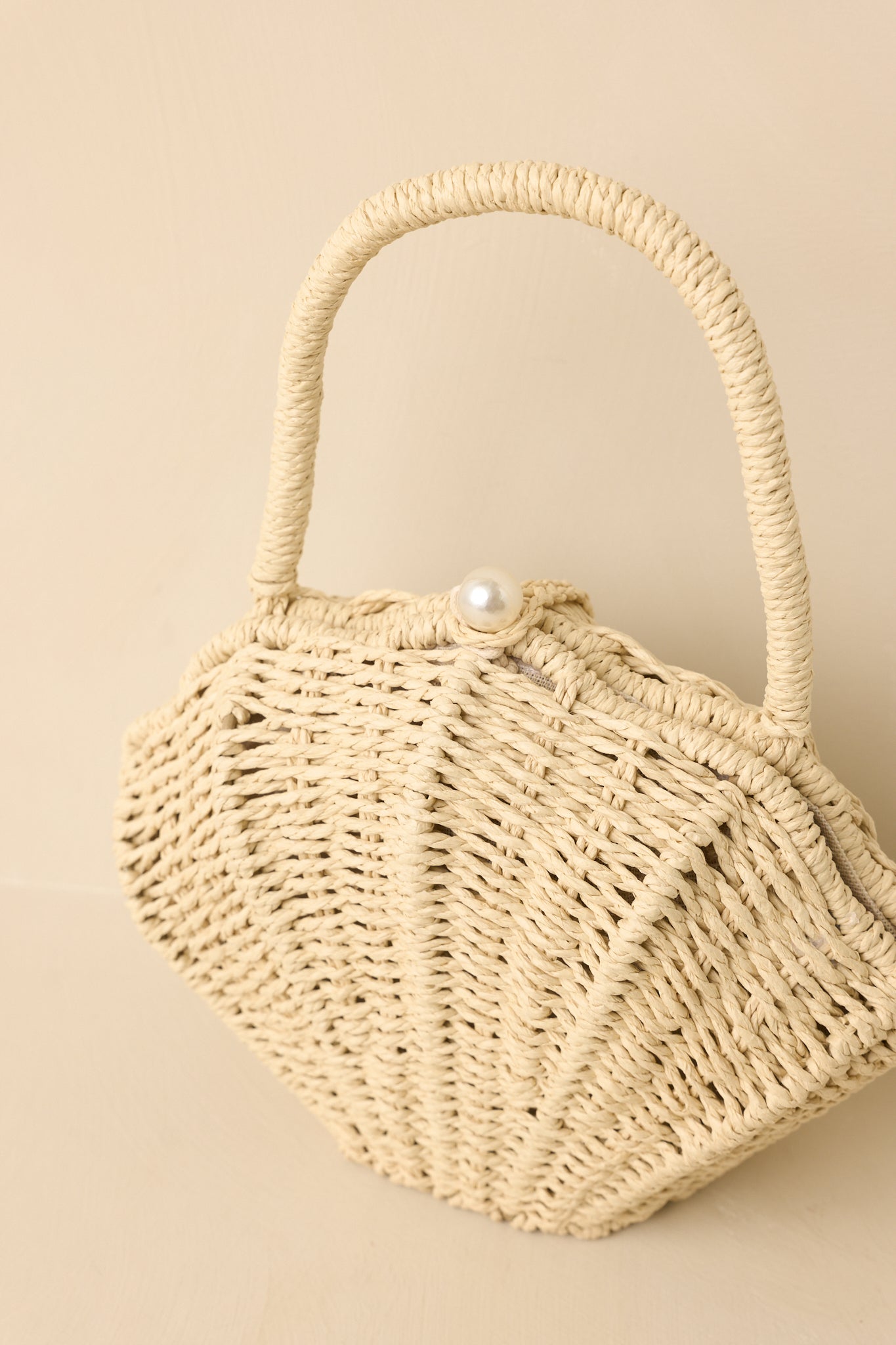 Detailed close-up of woven handbag showcasing intricate basket weave texture and top closure detail.