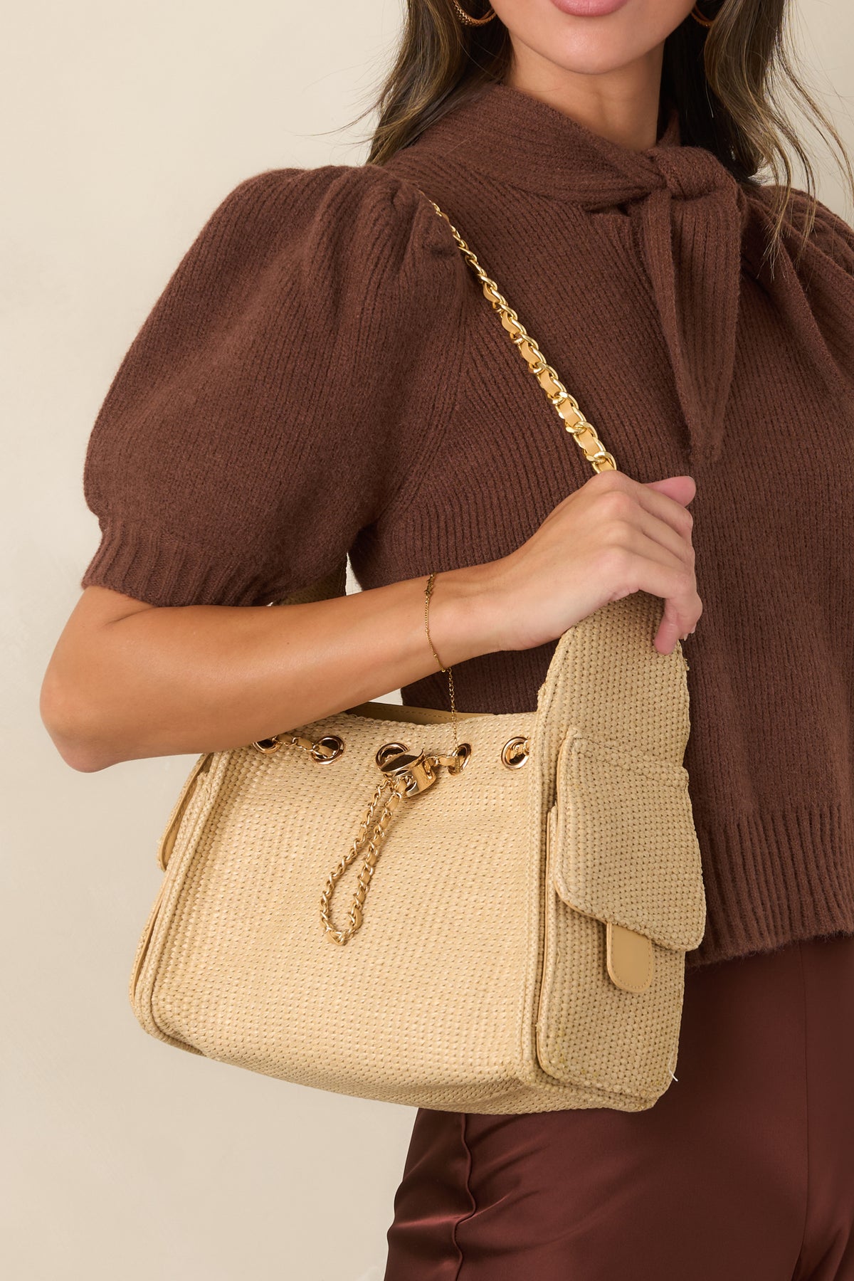 Woven handbag featuring polished gold-tone hardware, an adjustable chain shoulder strap, and two exterior side pockets with magnetic flap closures.