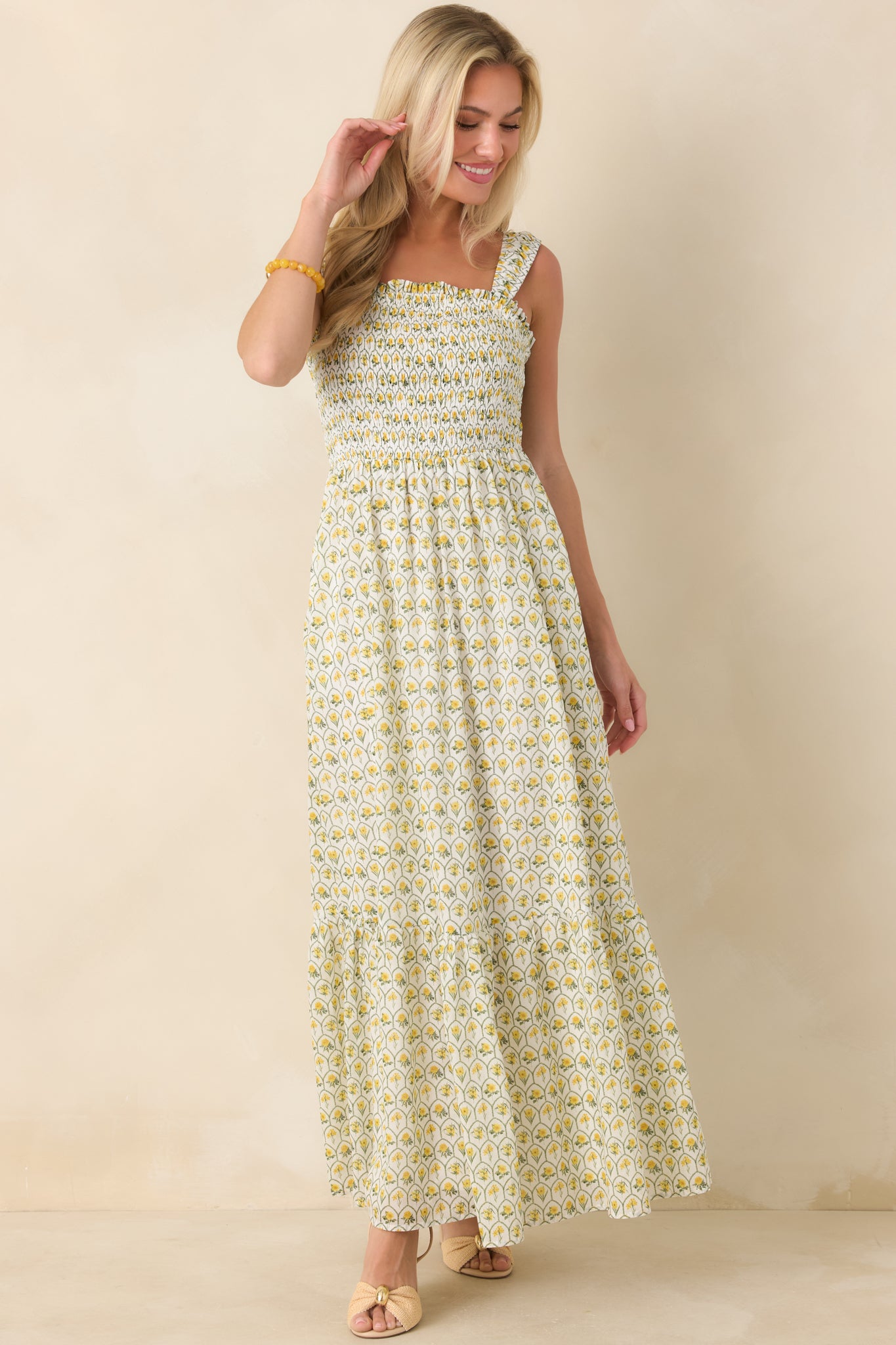 Yellow cotton maxi dress showcasing an allover multicolor floral pattern, wide shoulder straps, and a flattering smocked bodice above a tiered silhouette.