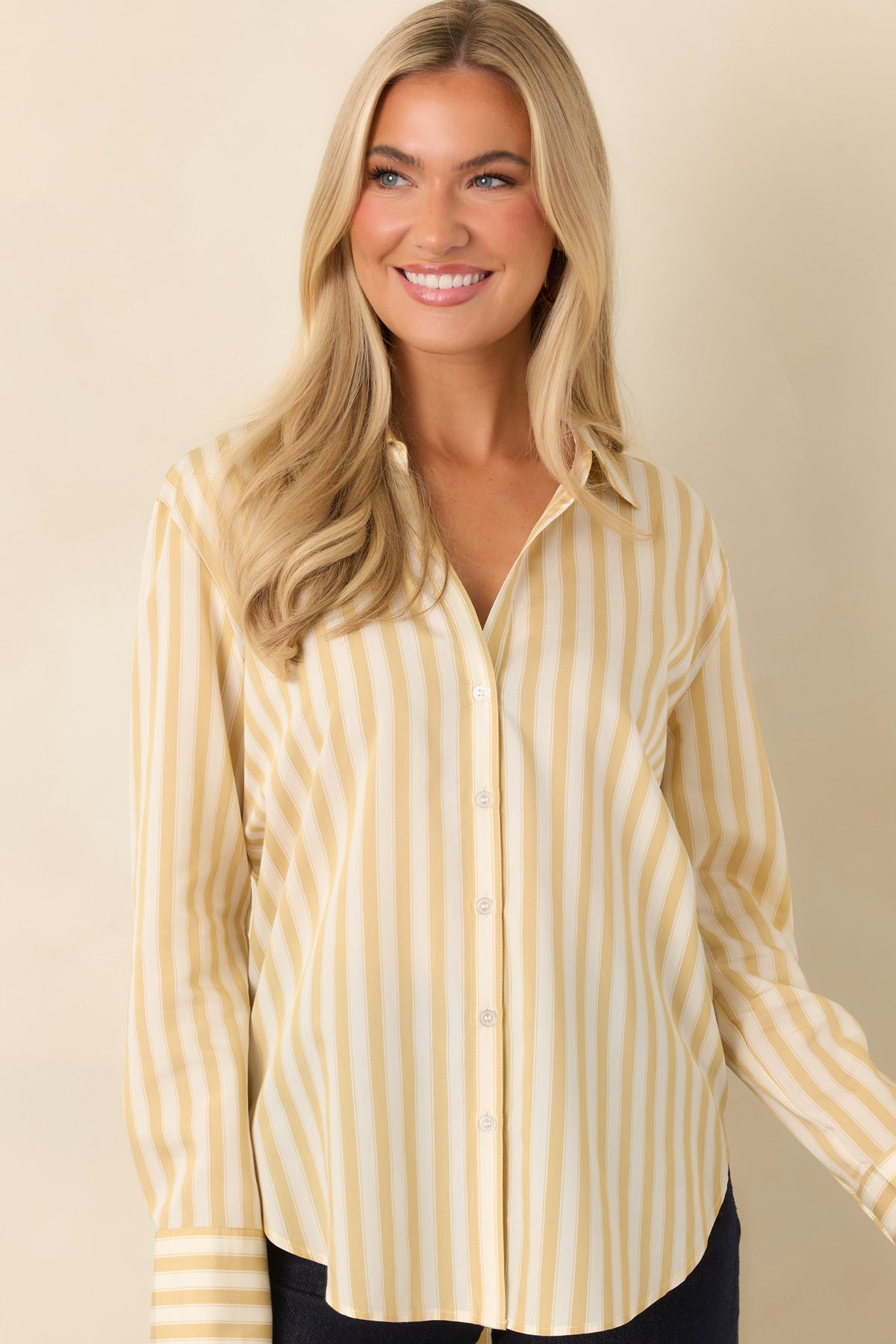 Yellow and ivory striped long sleeve shirt featuring a front button placket, pointed collar, and curved bottom hem.