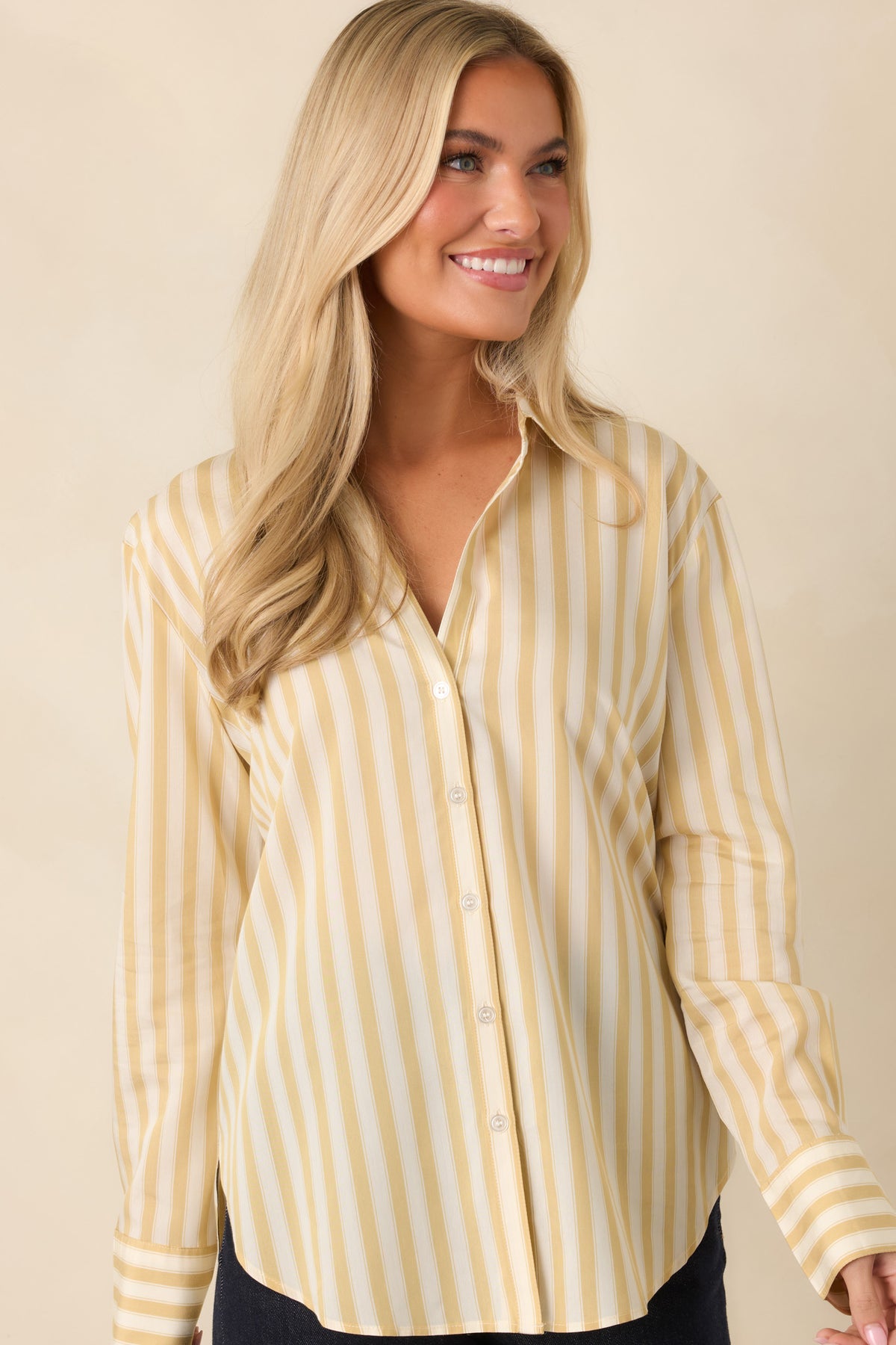 Yellow and ivory striped button-down shirt featuring a relaxed fit, curved shirttail hem, and long sleeves with wide cuffs.