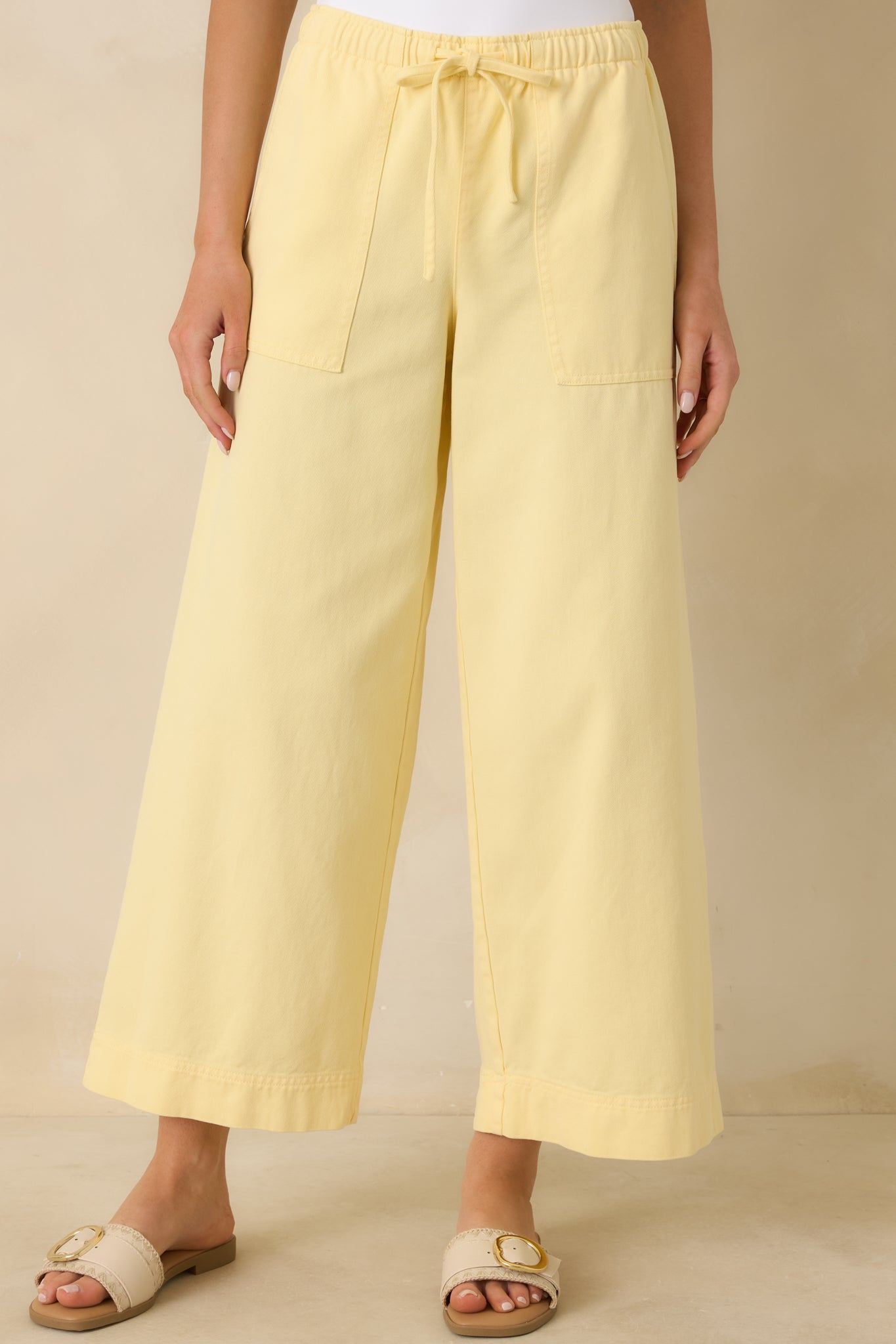 Yellow pants emphasizing the relaxed fit and smooth flow of the fabric through the legs.