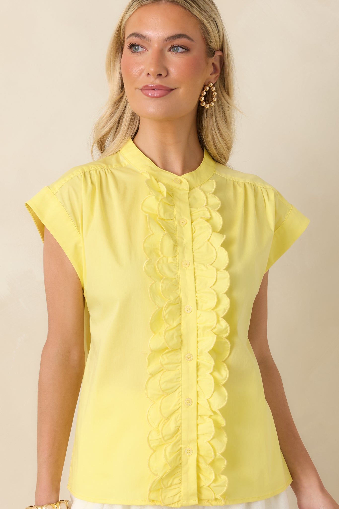 Yellow top highlighting the scalloped ruffle front design and functional button-front closure set against a smooth cotton blend texture.