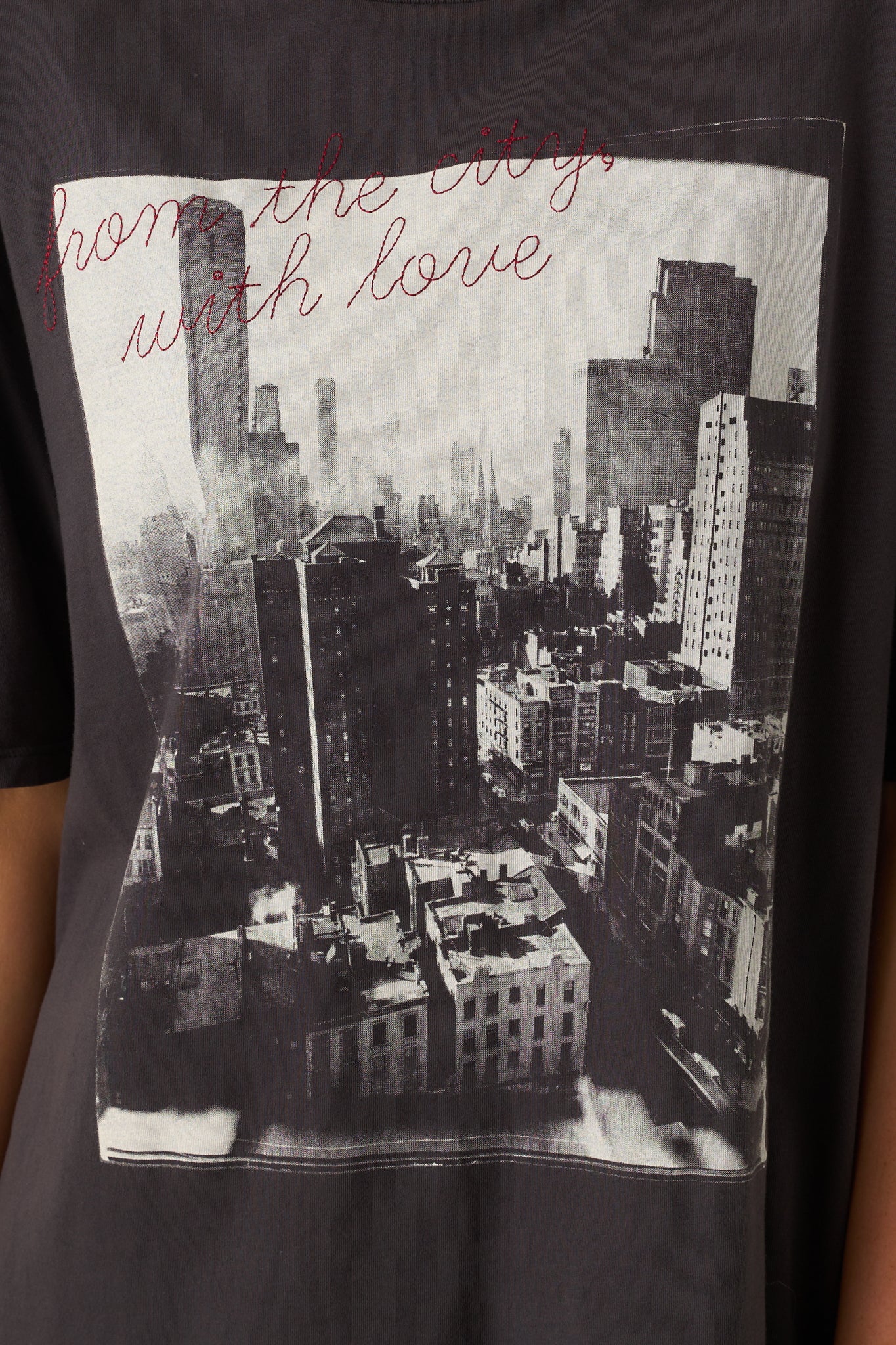 Zoomed detail of the black tee highlighting the embroidered red script and city graphic print.