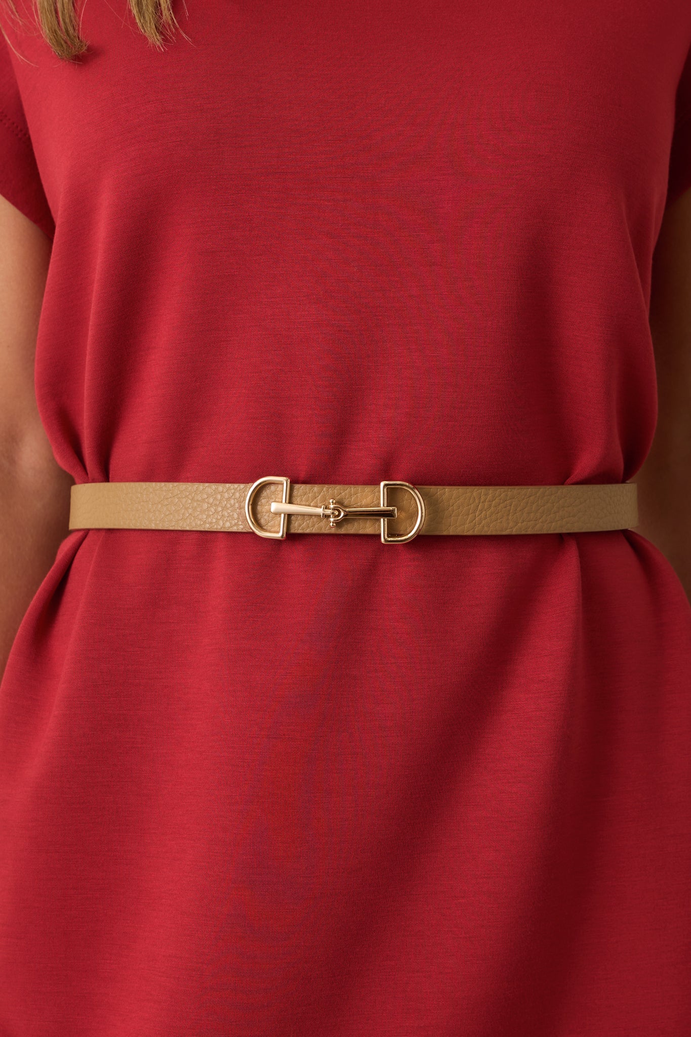 A zoomed-in detail of the gold hardware and textured finish on the camel brown belt.