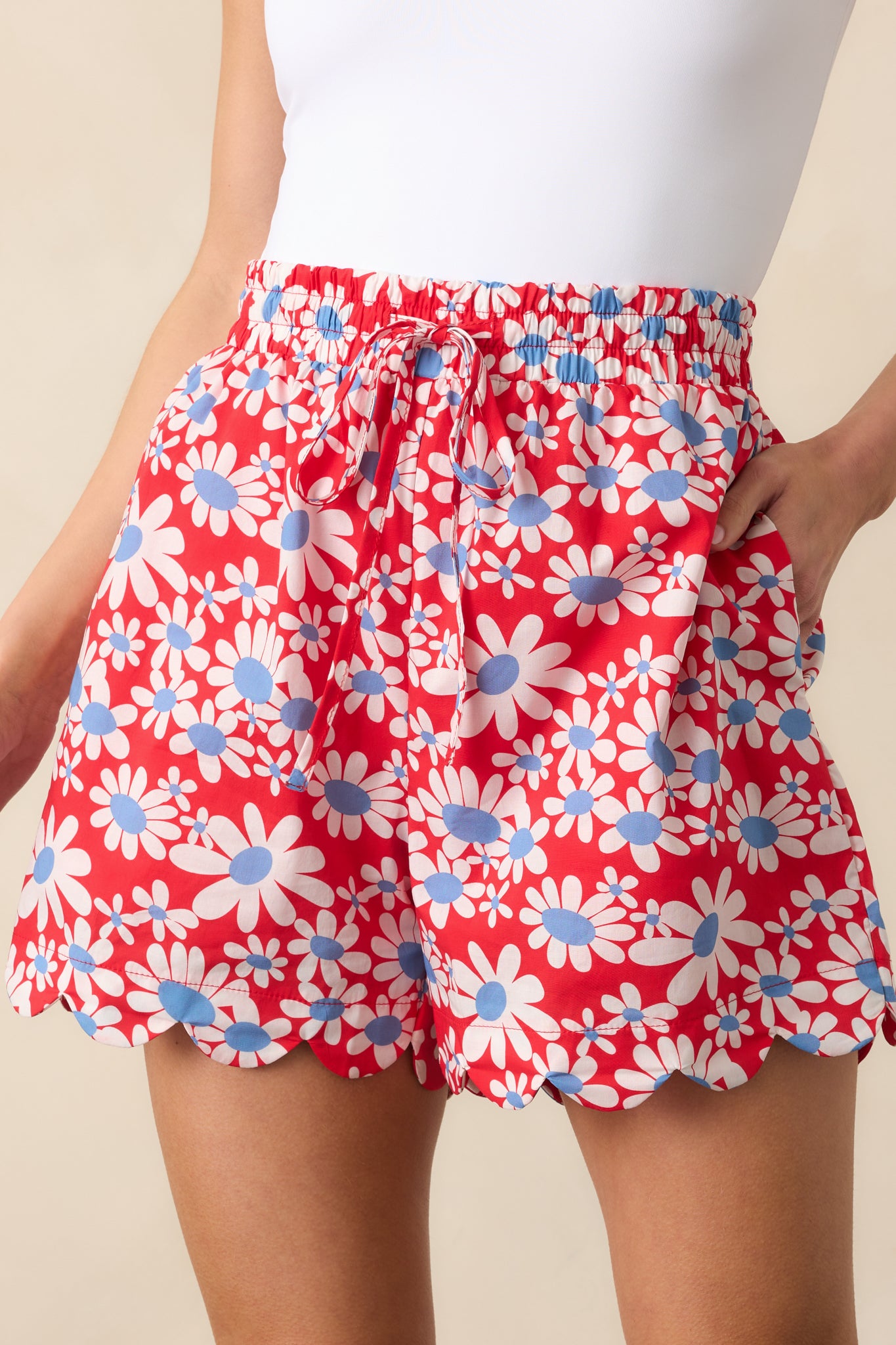 A zoomed-in shot of the red floral shorts showcasing the gathered elastic of the waistband, self-tie drawstring, and feminine touch.
