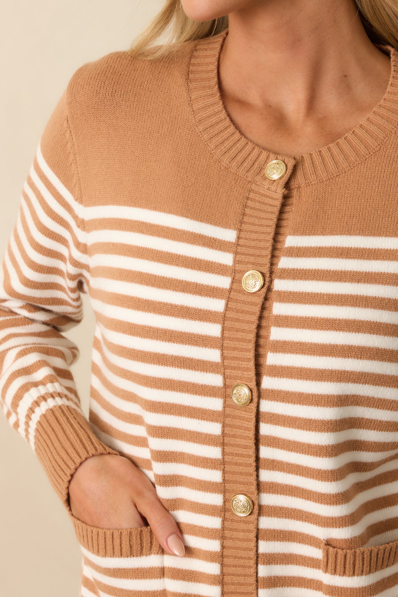 Zoomed-in view of the embossed gold-tone button front, ribbed hems, and ivory stripe pattern.