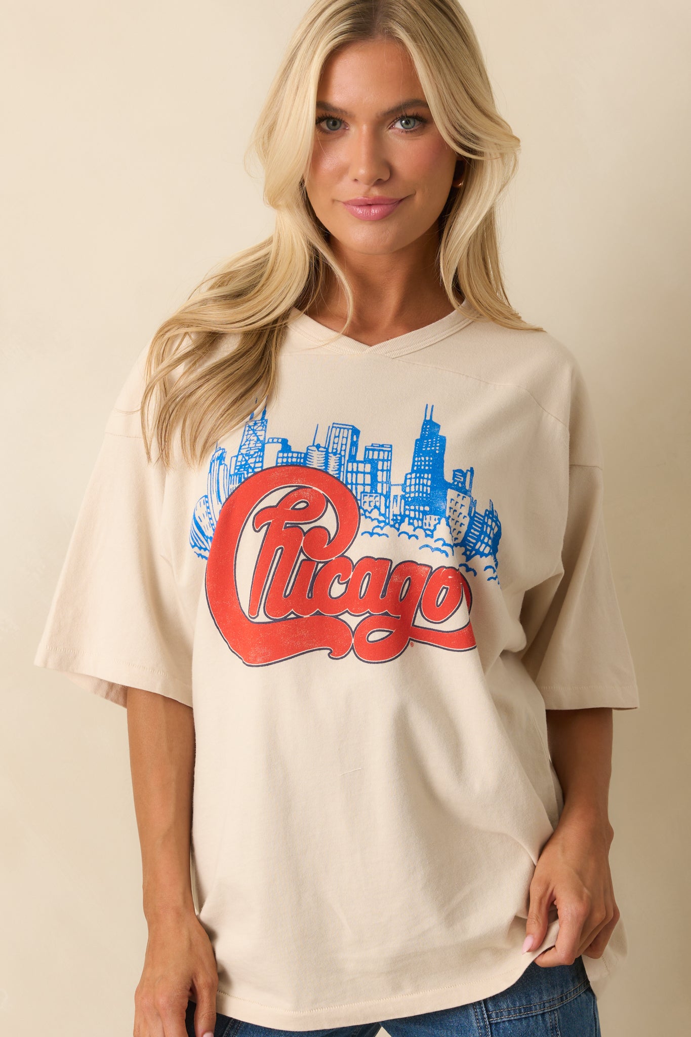Zoomed image on ivory T-shirt’s chest, emphasizing vivid blue skyline under bold red “Chicago” design.