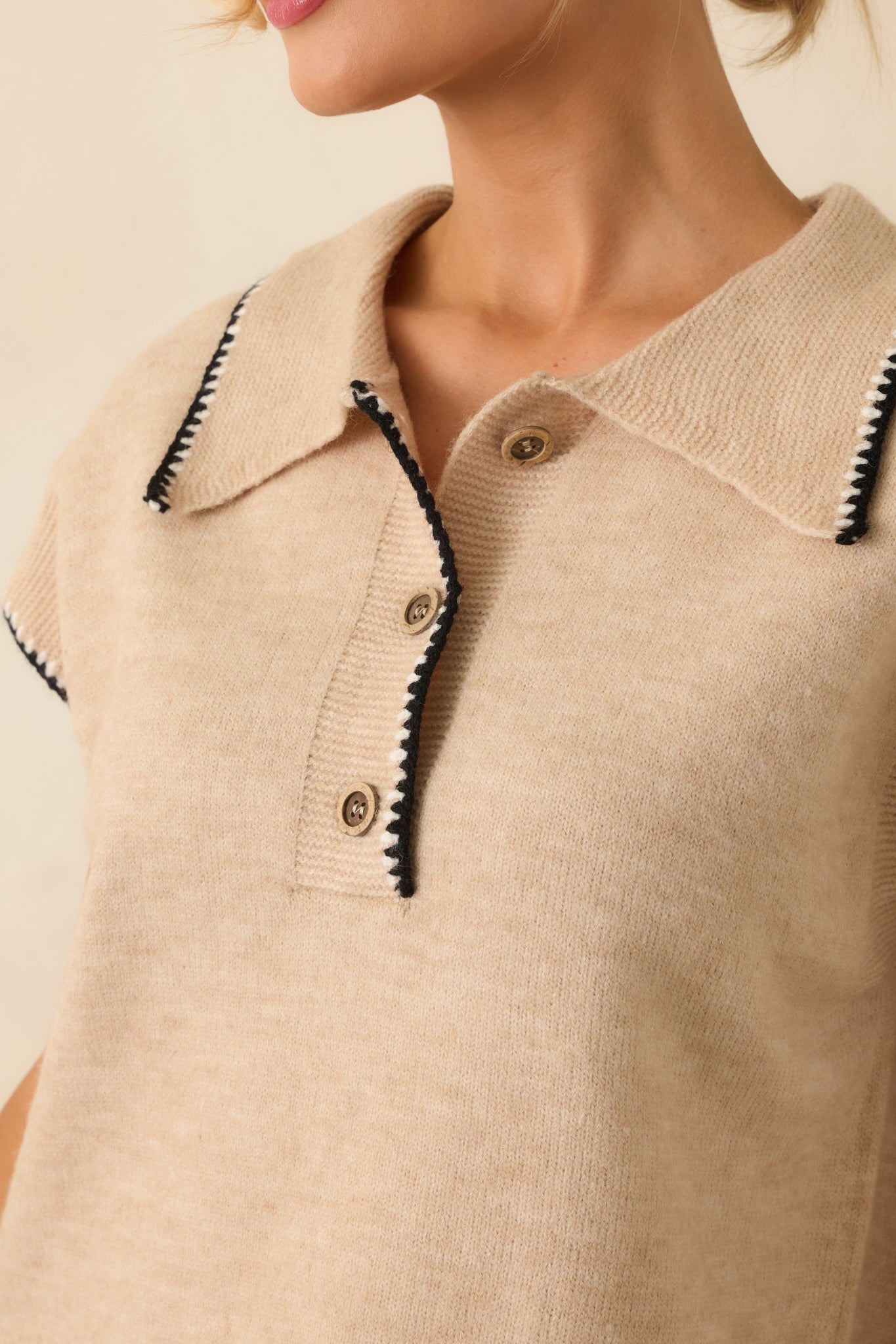 Zoomed-in view of the wood buttons, black whipstitch trim, and lightweight oatmeal knit fabric.