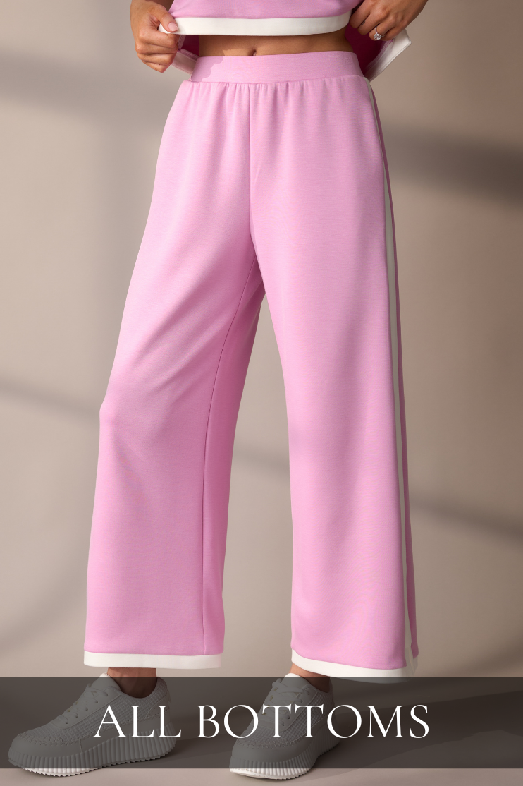 Woman wearing pink wide-leg pants with white sneakers, linking to the All Bottoms shop.