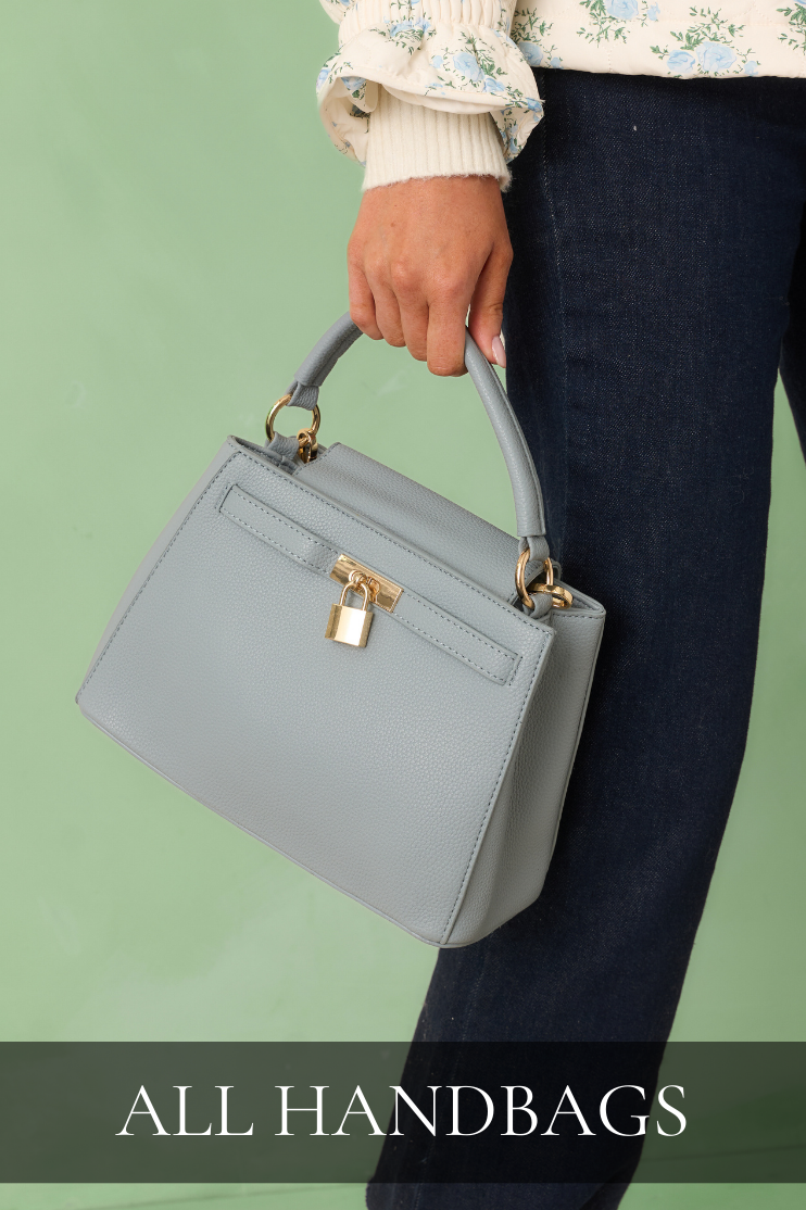 Woman holding a structured gray handbag with gold hardware, linking to the All Handbags shop.