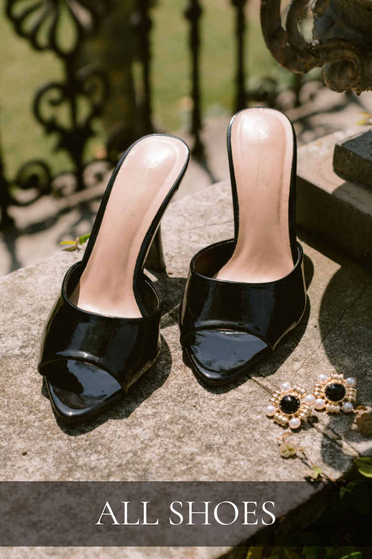 Pair of black patent leather heeled sandals displayed outdoors. Heels are featured in All Shoes Collection.