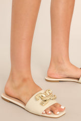 These sandals feature a slip on style, and a large gold buckle-like design.
