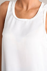 Close up view of this white tank top that showcases a classic scoop neckline, stylish slits up the sides of the bottom hem, and a lightweight fabric for effortless comfort and style.