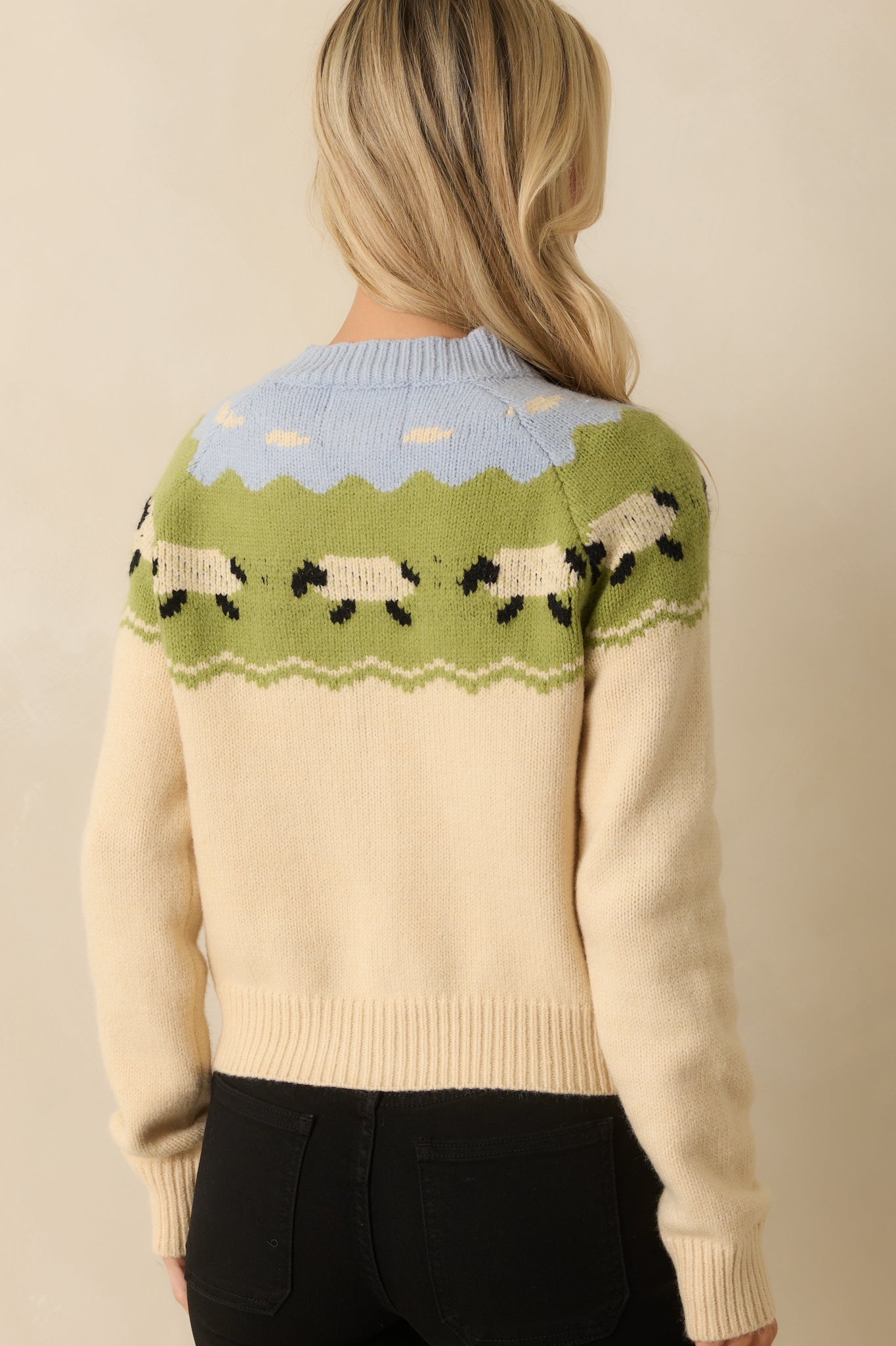 Back view of ecru cardigan with plain knit body and patterned yoke across shoulders.