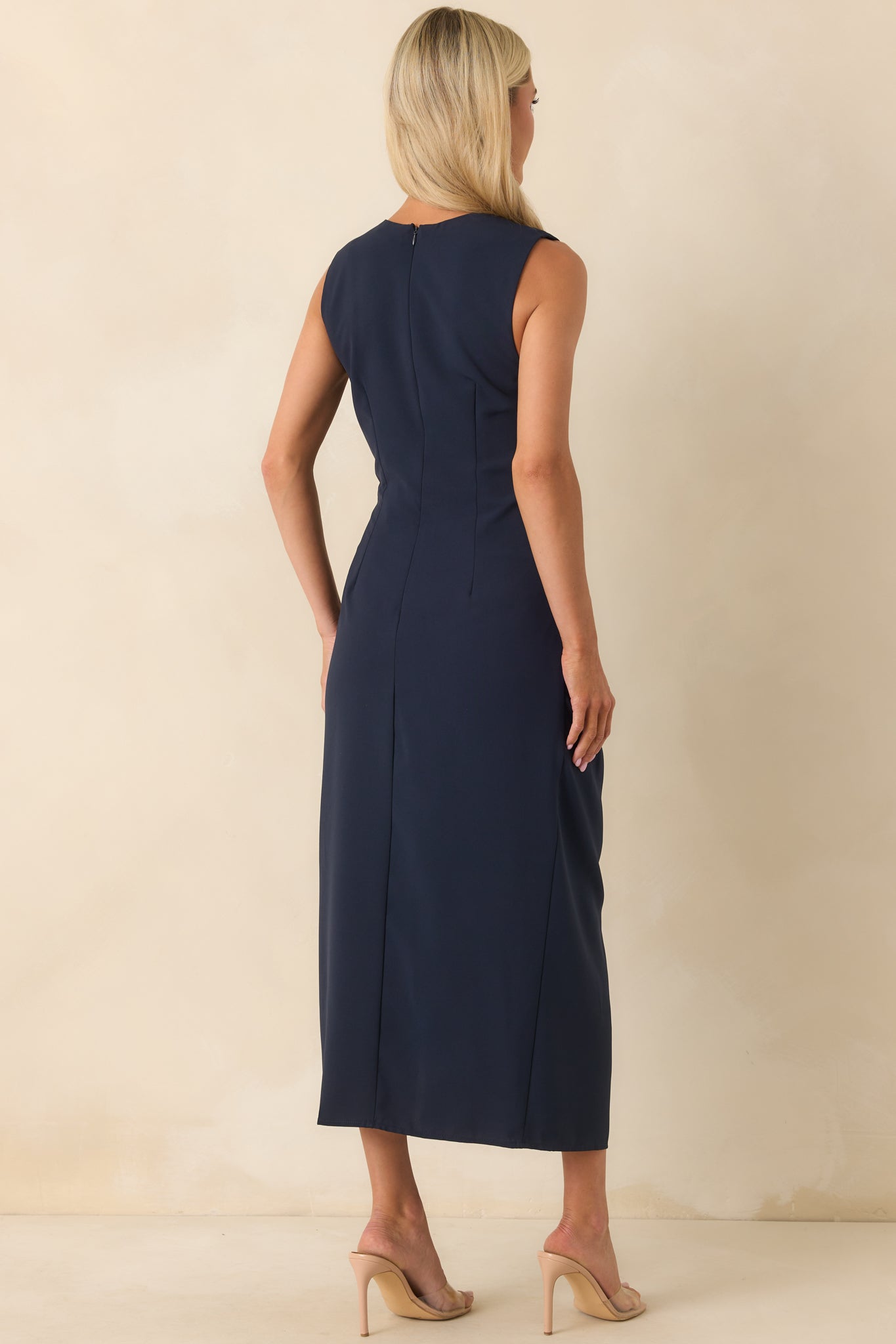 A view from behind of the navy sleeveless dress, showing the smooth fabric and fitted shape at the back.