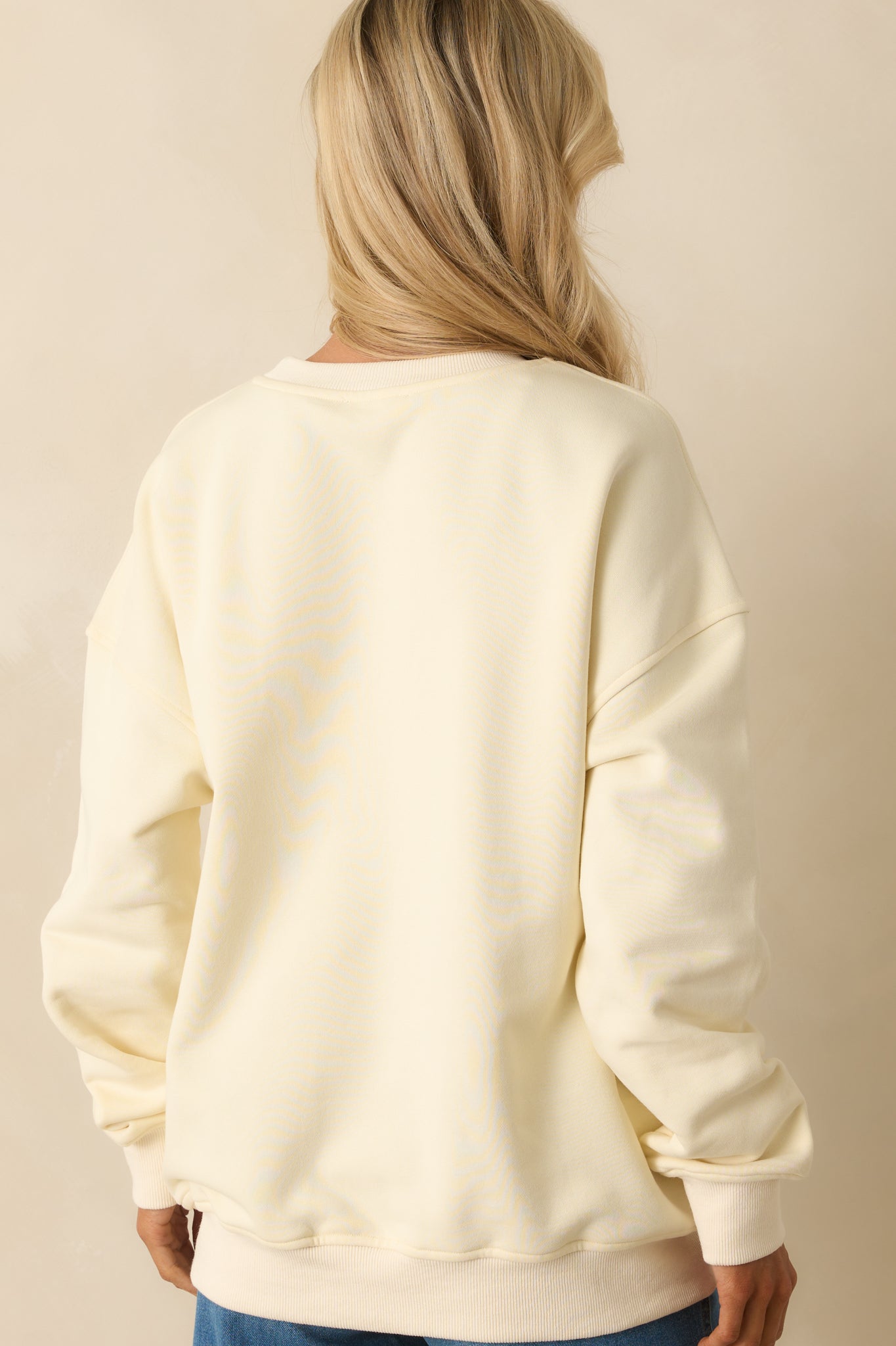 Back view of plain ivory cotton sweatshirt with drop-shoulder design and ribbed hems.